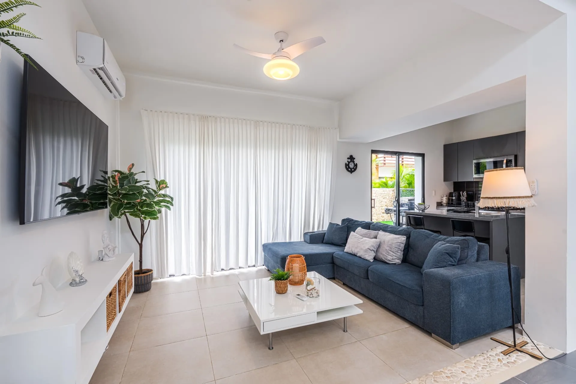Villa living room with blue sectional sofa, white media console and open kitchen beyond