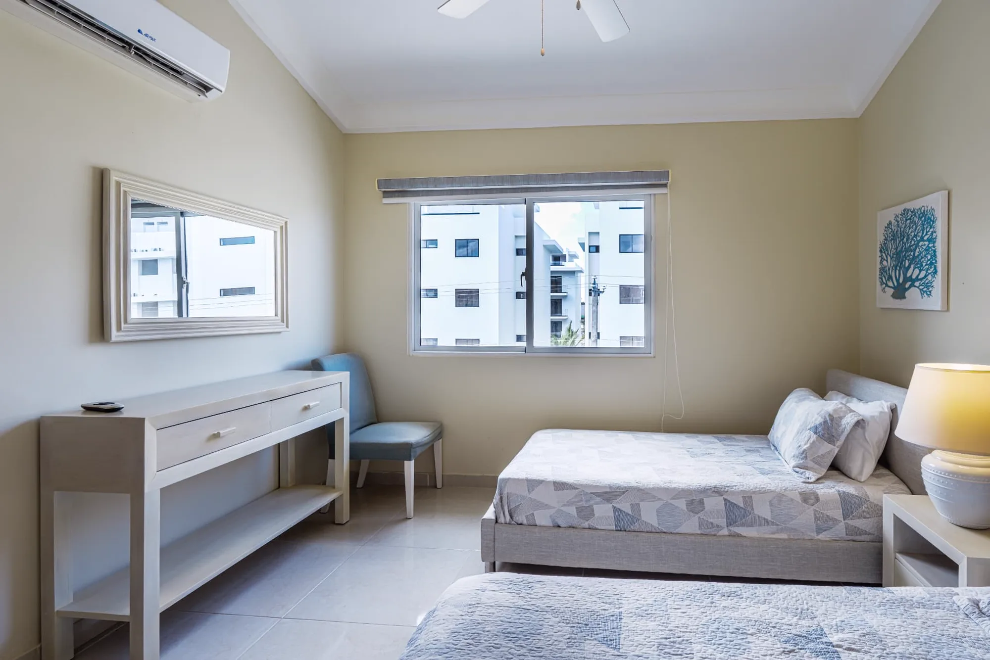 Second view of the twin bedroom with console table, framed mirror, accent chair and garden view window