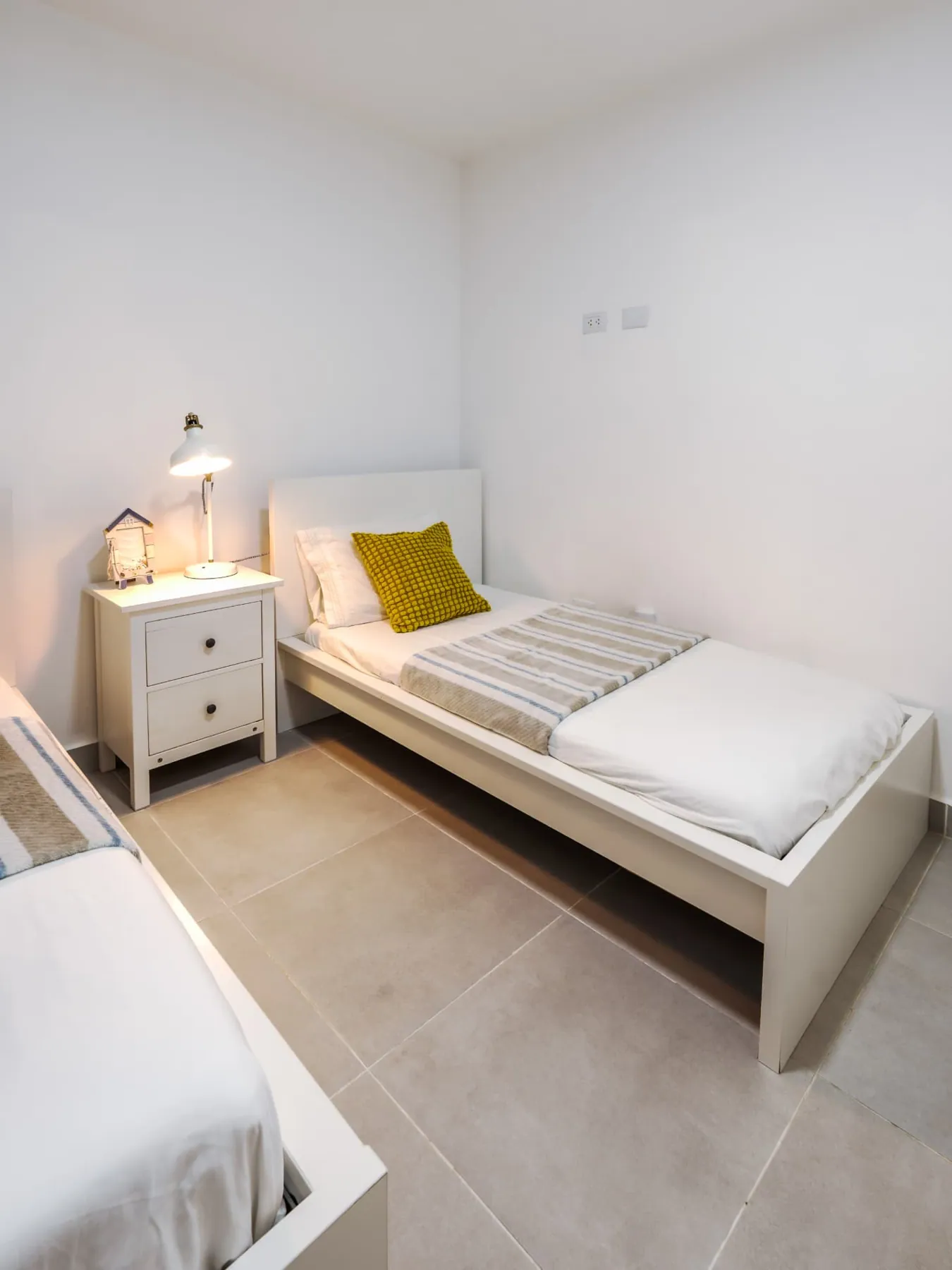 Second bedroom with two twin beds, white nightstand and reading lamp