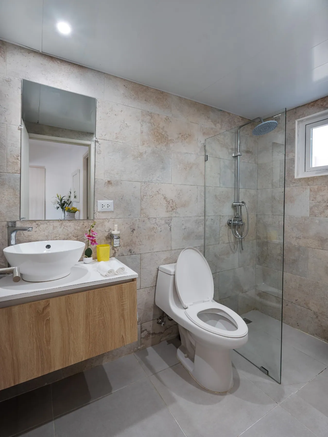 Second travertine bathroom with vessel sink, large mirror and glass rain shower