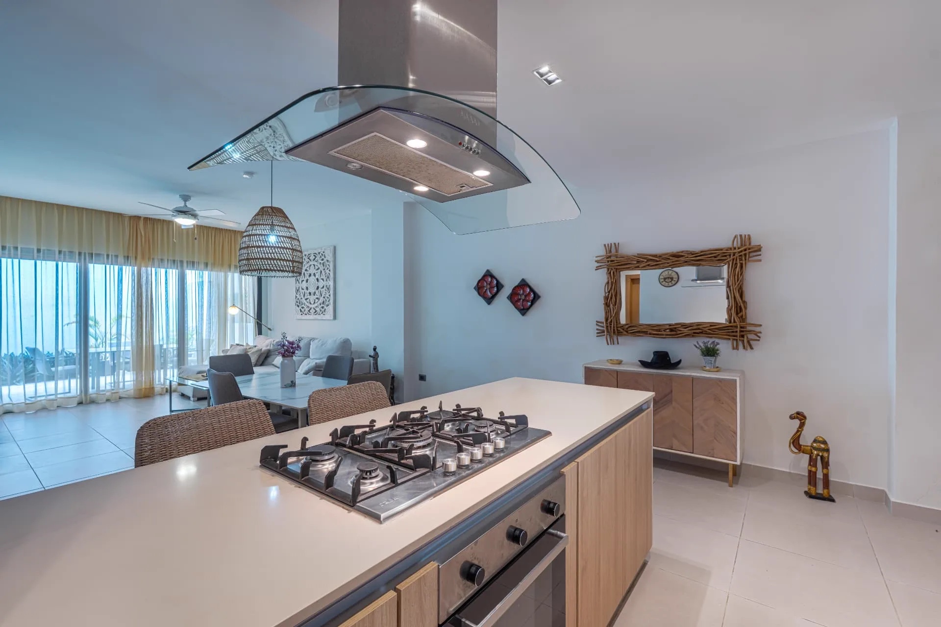 Kitchen island with gas cooktop and curved glass extractor hood opening onto the living area