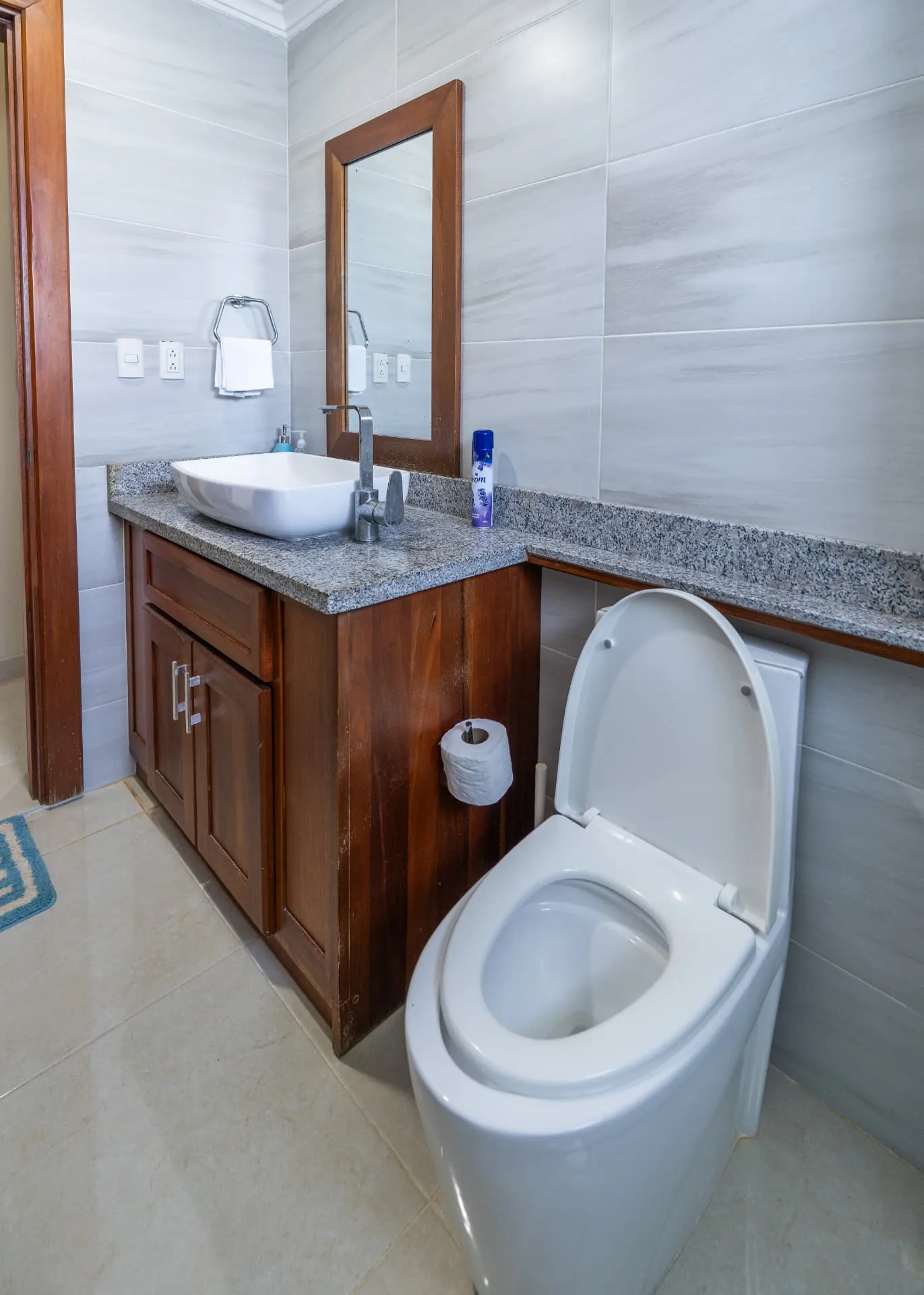 Guest bathroom at Eden with vessel basin on granite, mahogany vanity and framed mirror on marbled tile