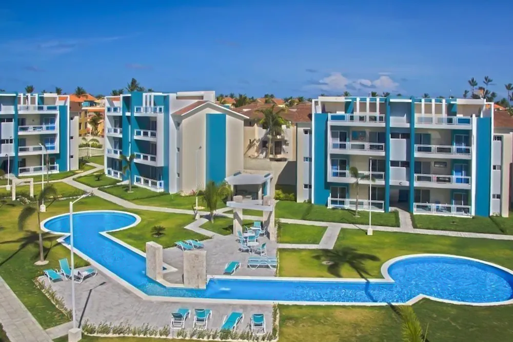 Turquoise and white apartment buildings at Eden framing the curved pools, loungers and landscaped lawns