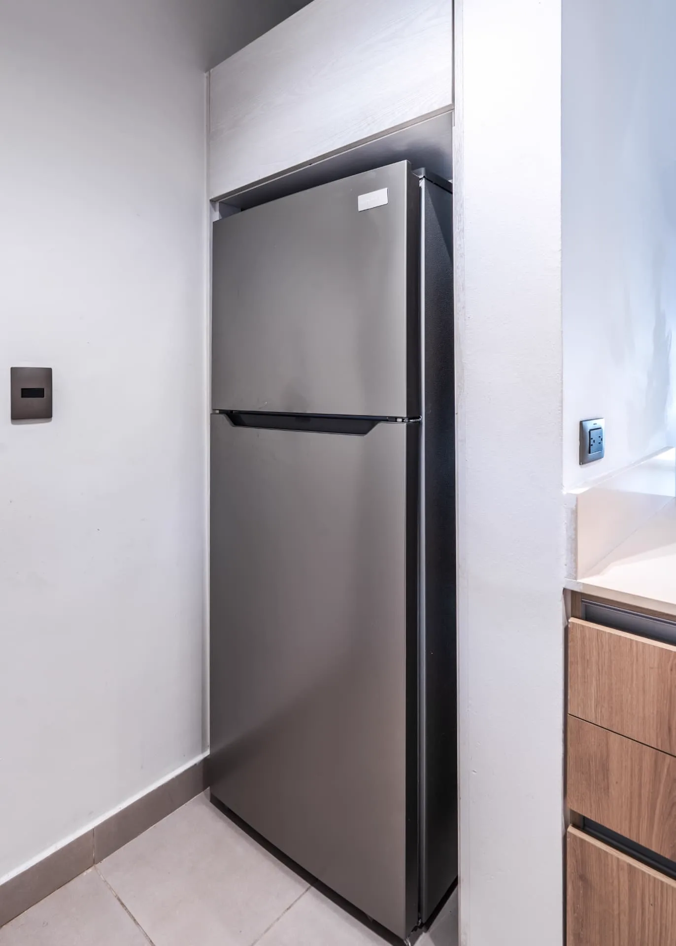 Recessed kitchen nook with a stainless steel refrigerator beside timber cabinetry