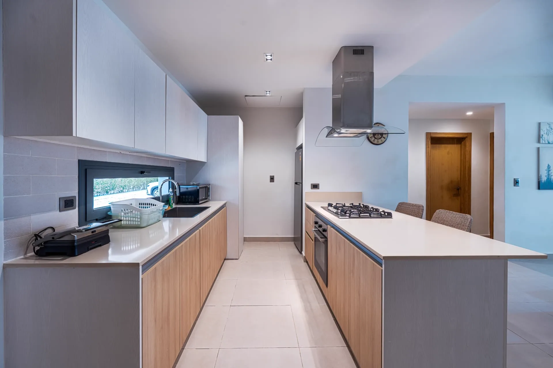 Galley kitchen with pale timber cabinetry, quartz counters and a long island with seating