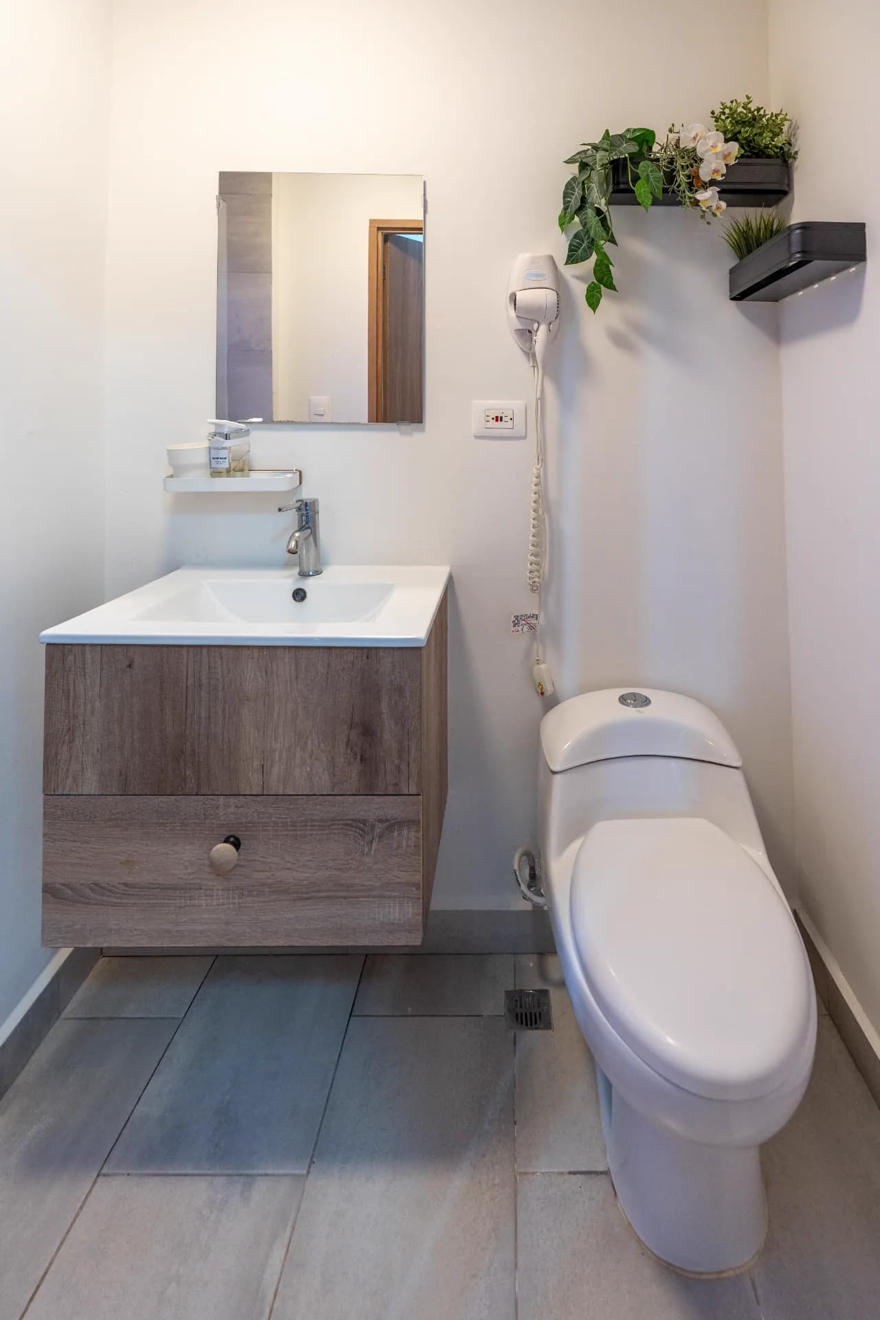 Powder room with floating oak vanity, framed mirror and hanging planters