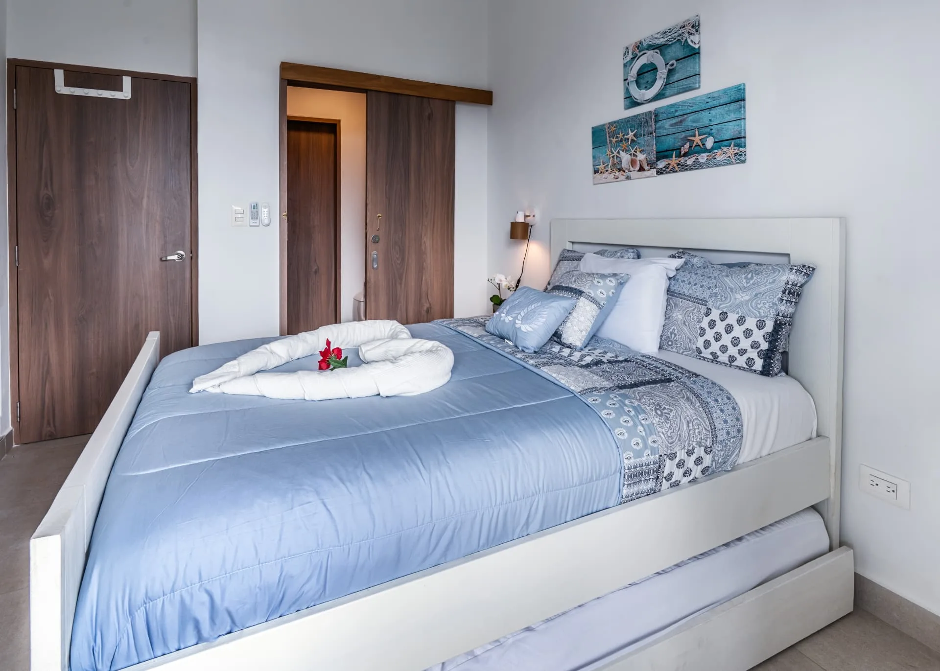 Bedroom with trundle bed, blue linens and walnut wardrobe doors