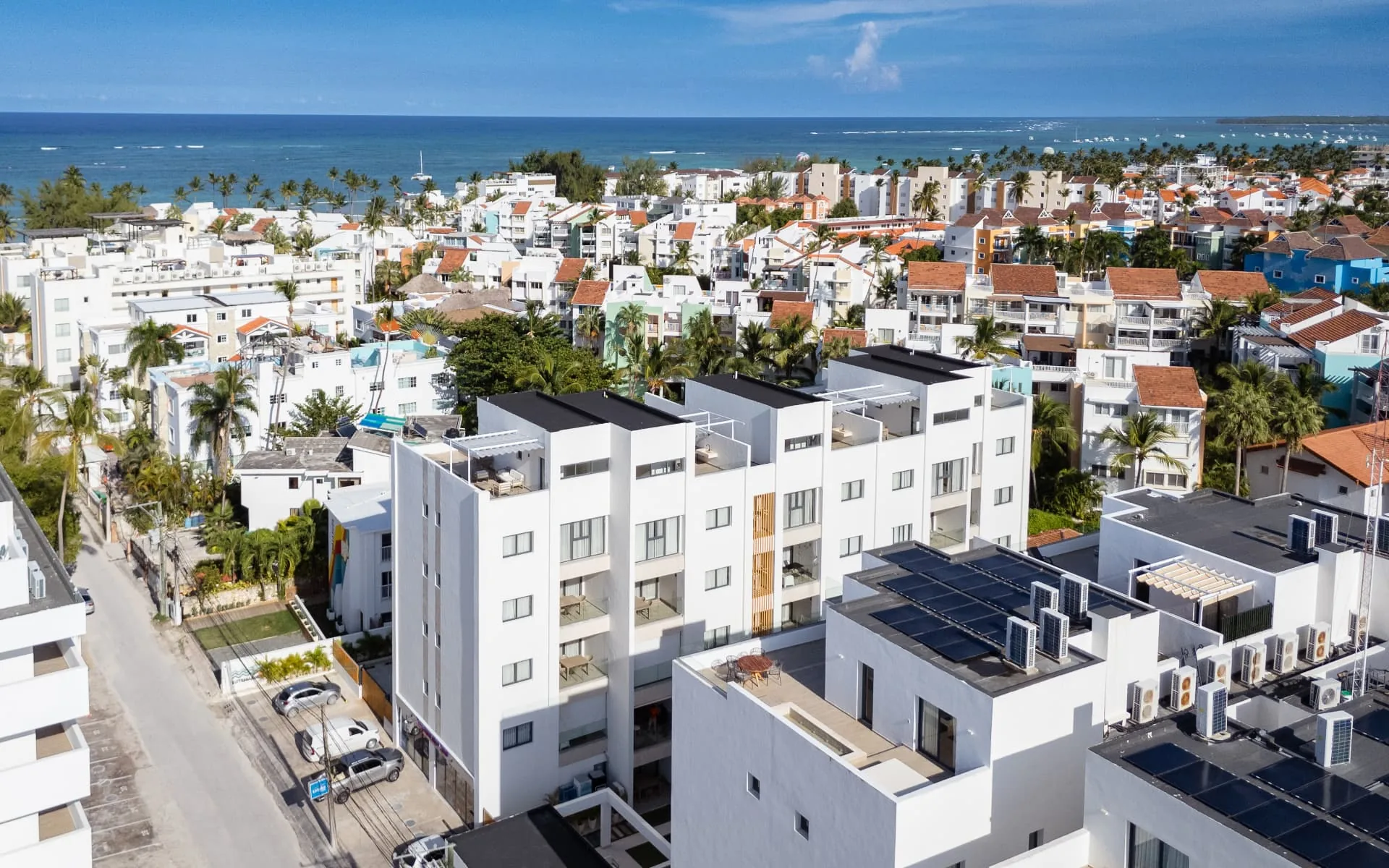 Aerial view of a modern white apartment building with the turquoise Caribbean coastline behind
