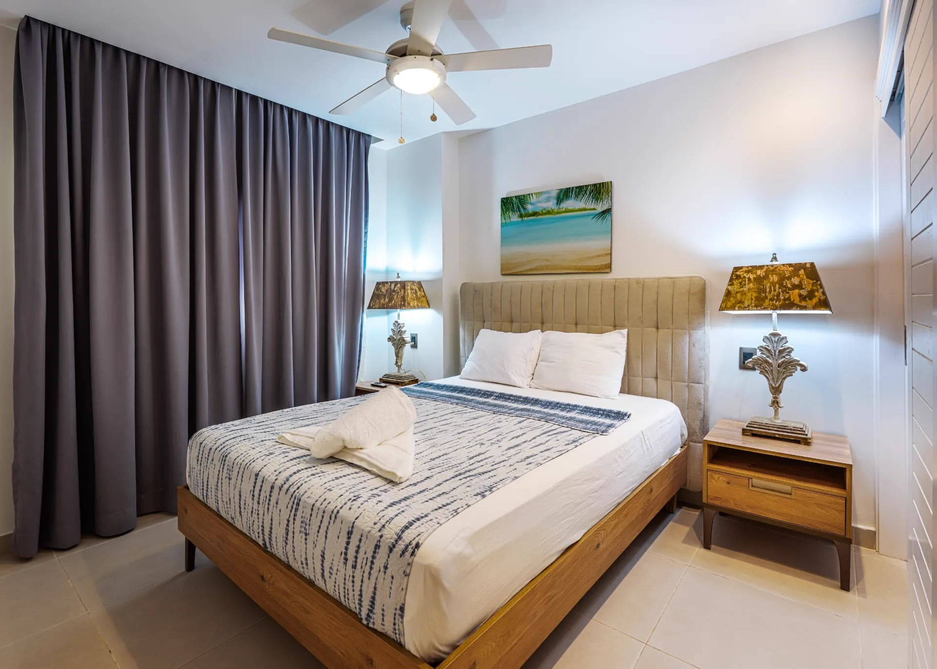 Primary bedroom with tufted headboard, patterned bedding and matching bedside lamps