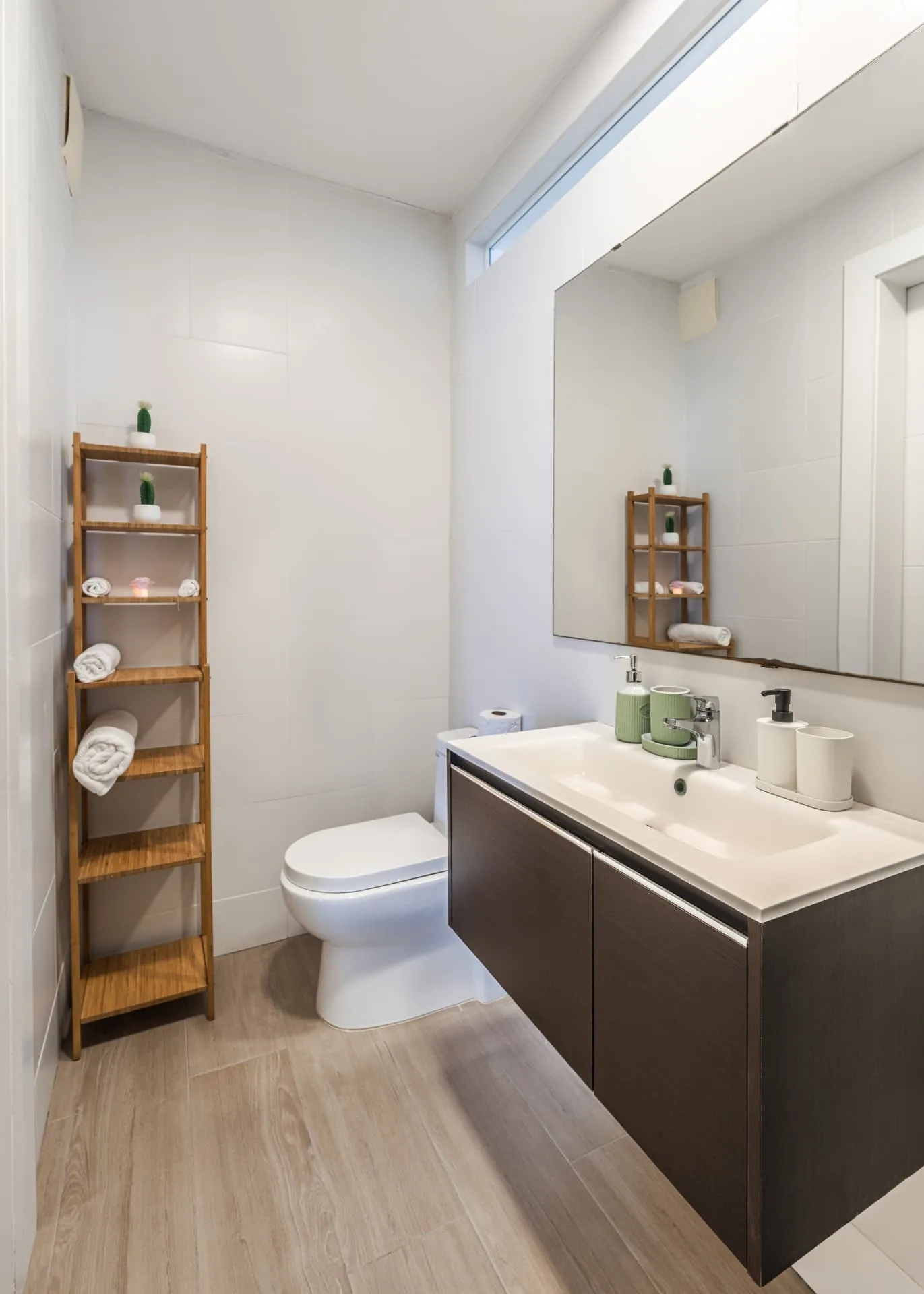 Bright bathroom with floating dark timber vanity, large mirror and bamboo towel shelving