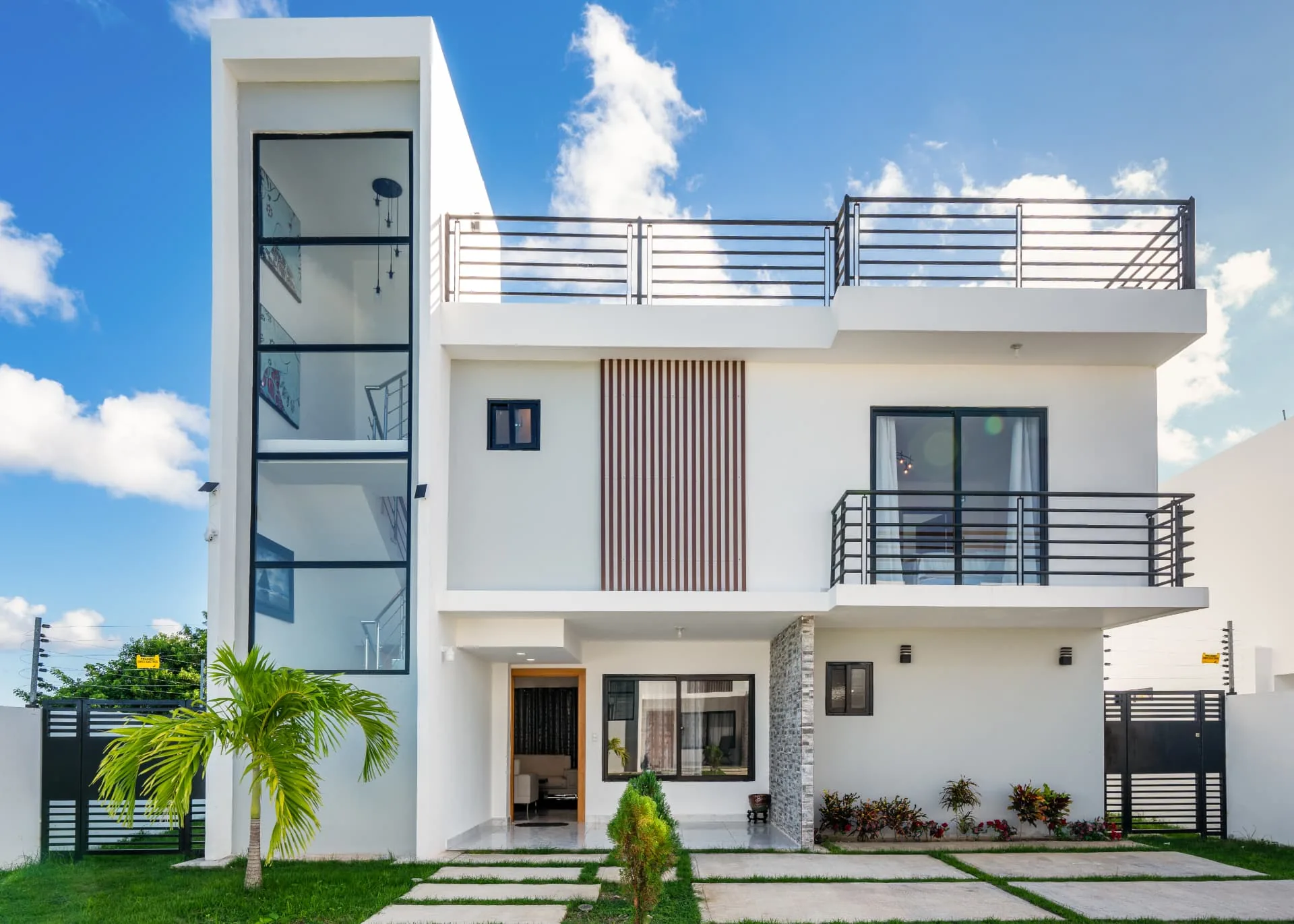 Modern white villa facade with timber slat detail, glass stair tower and rooftop terrace