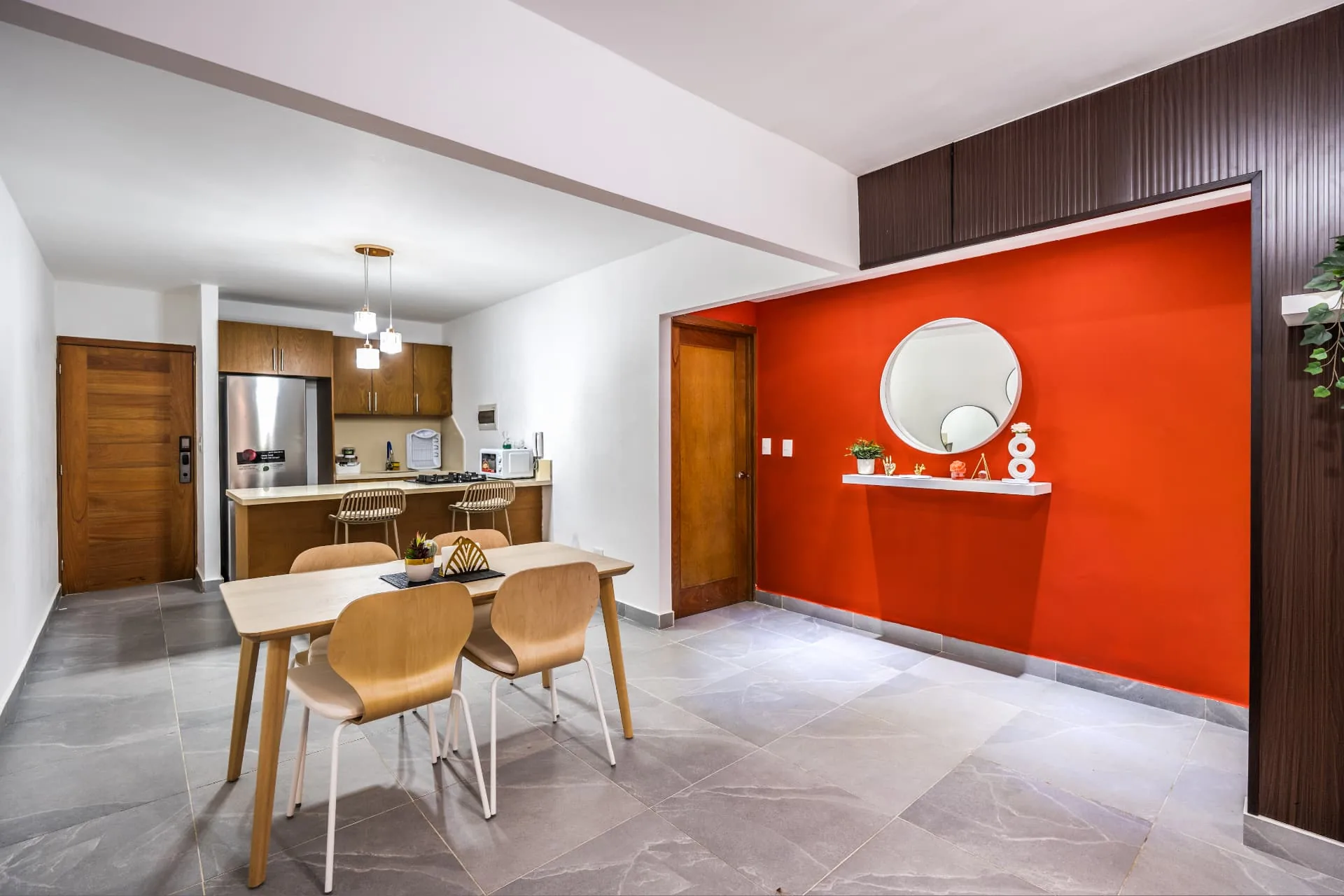 Apartment dining area with timber table, kitchen bar and terracotta feature wall