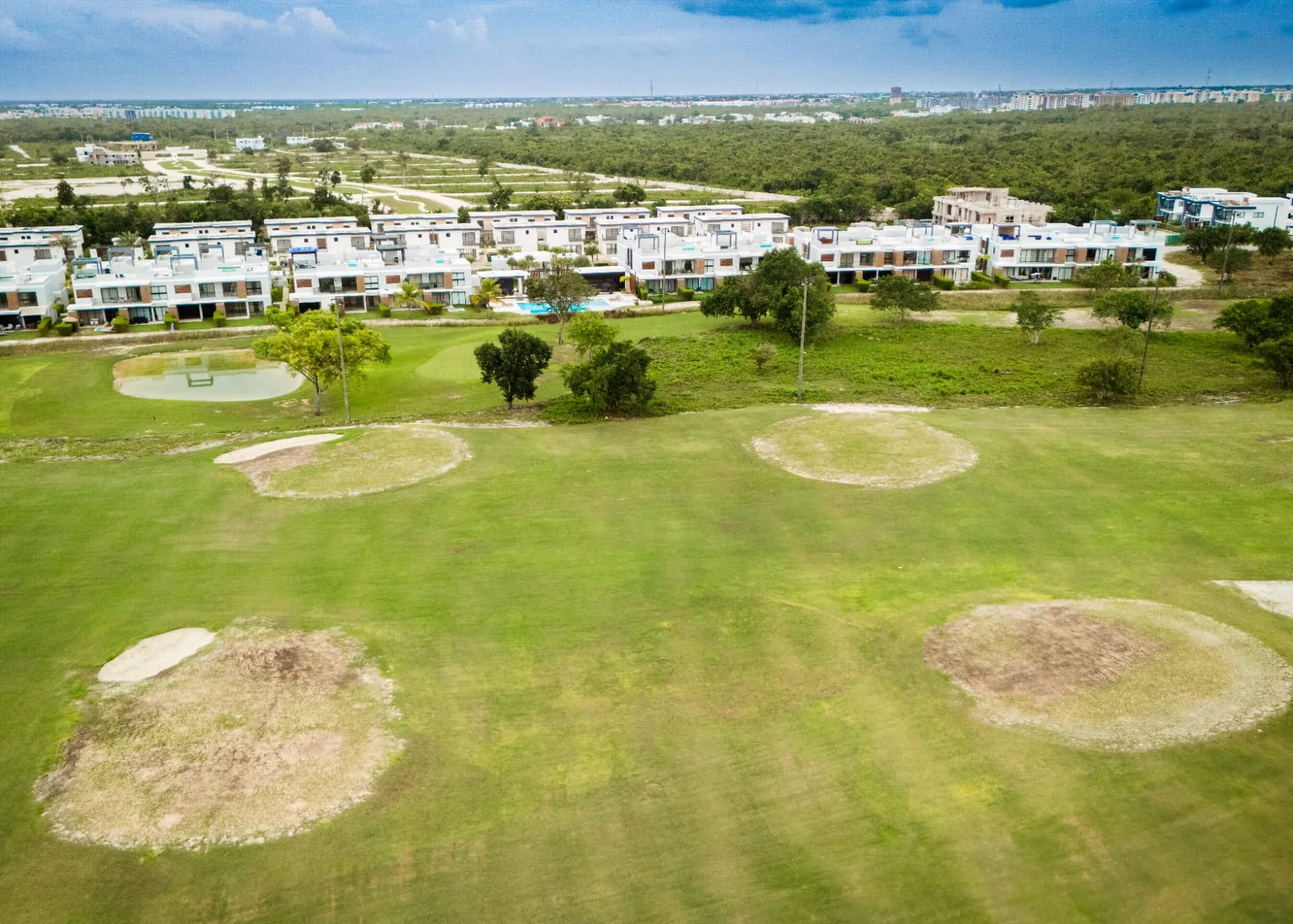 Aerial view of modern villas lining a golf course fairway in Punta Cana