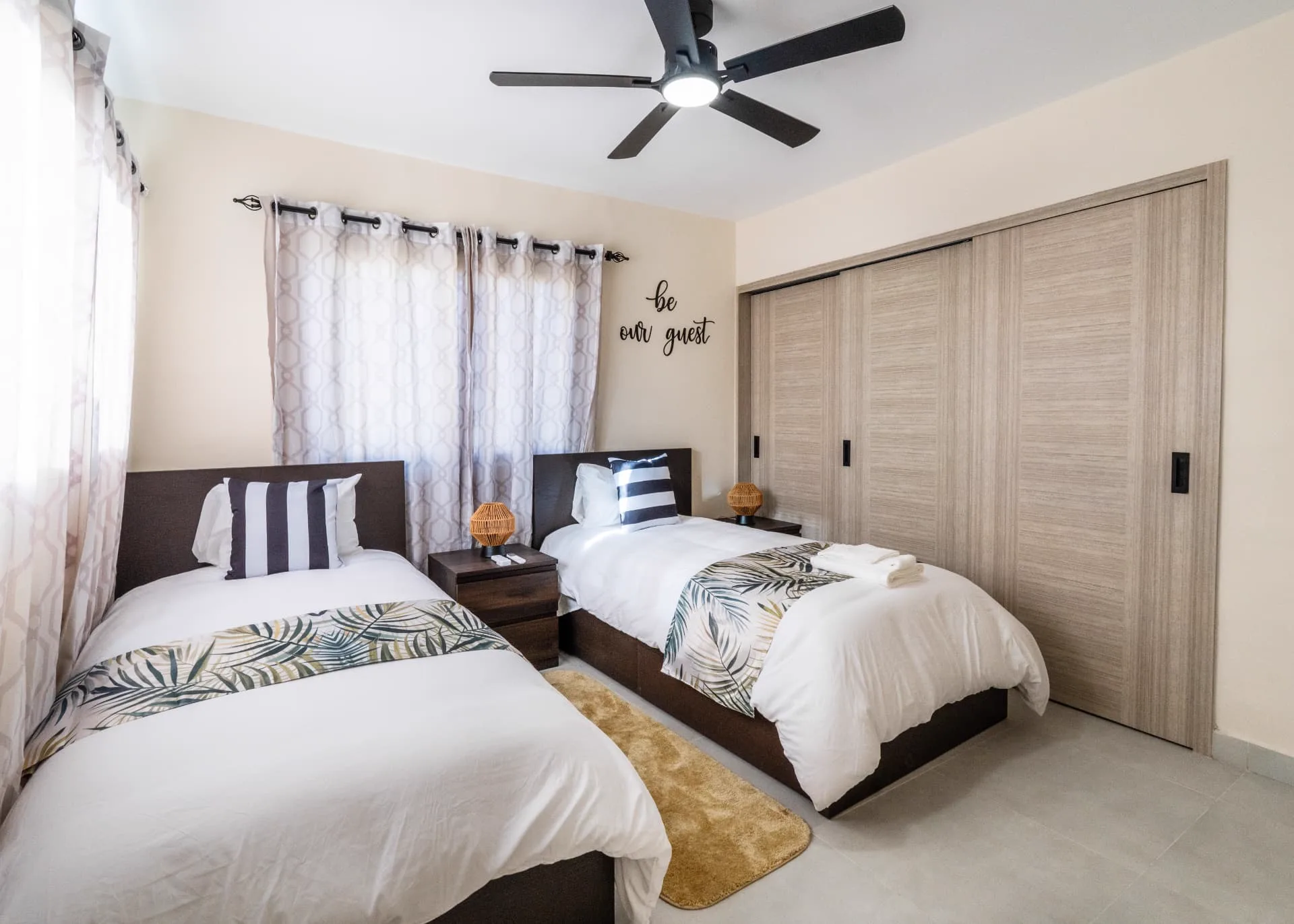 Second view of the twin bedroom showing the full-width sliding wardrobe and patterned curtains