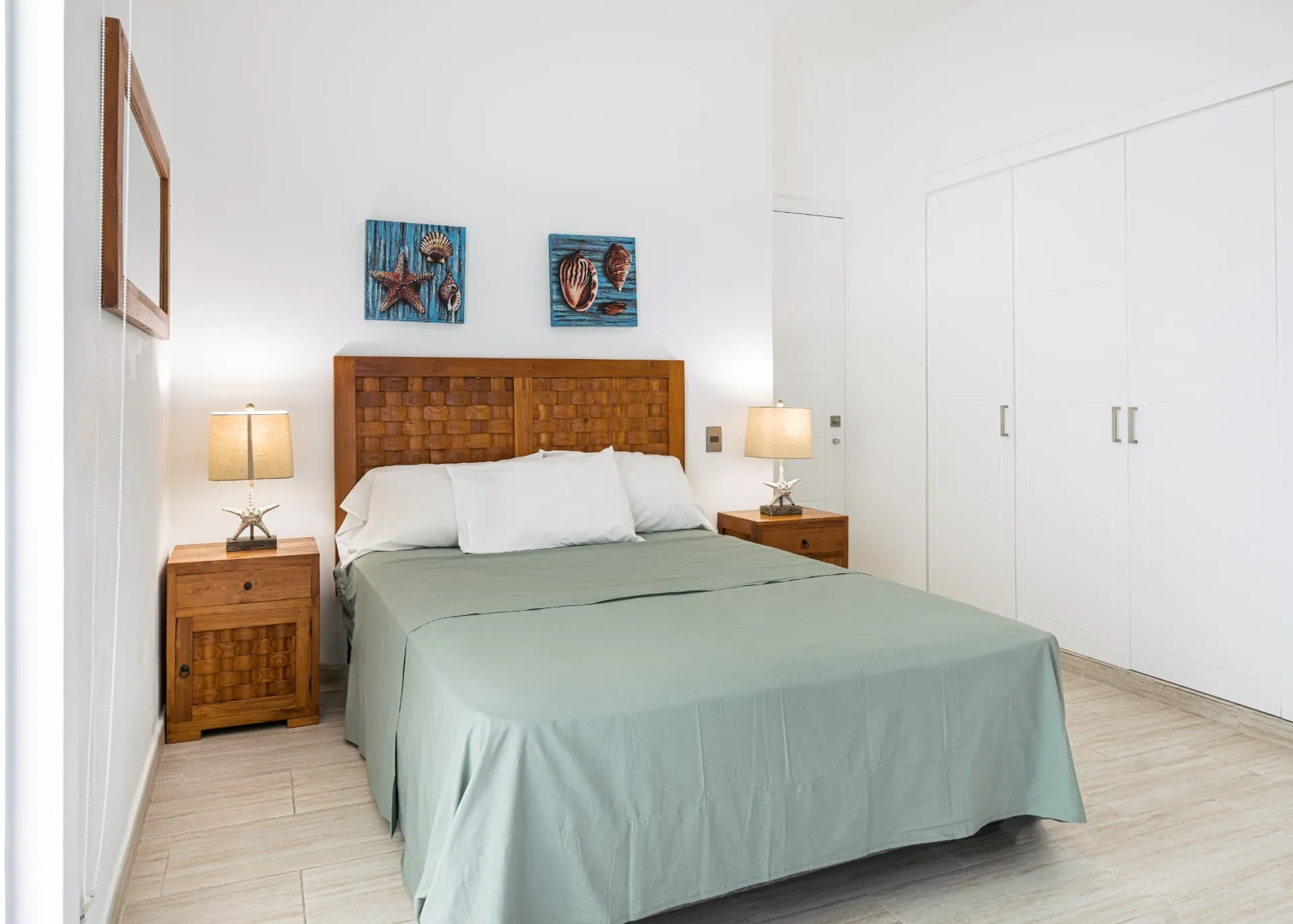 Bright villa bedroom with light timber furniture and coastal wall art