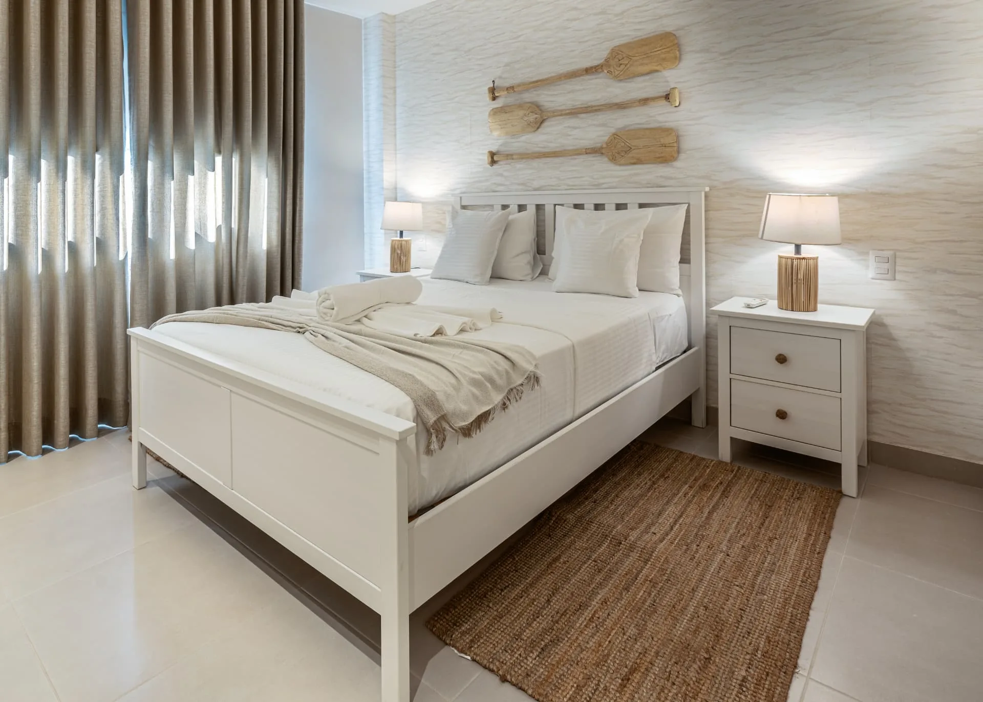 Coastal guest bedroom with white bedframe, textured wall, paddle wall art and jute runner