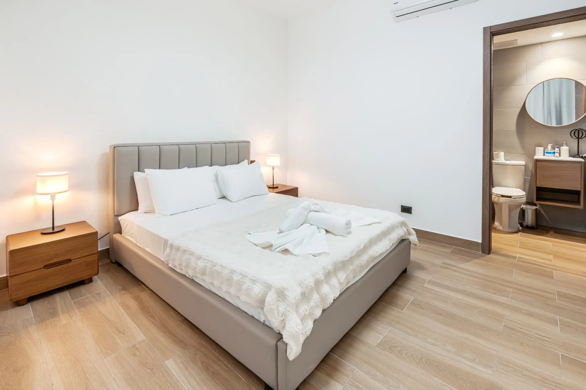 Second bedroom with king bed, bedside lamps and an open door to the en-suite bathroom