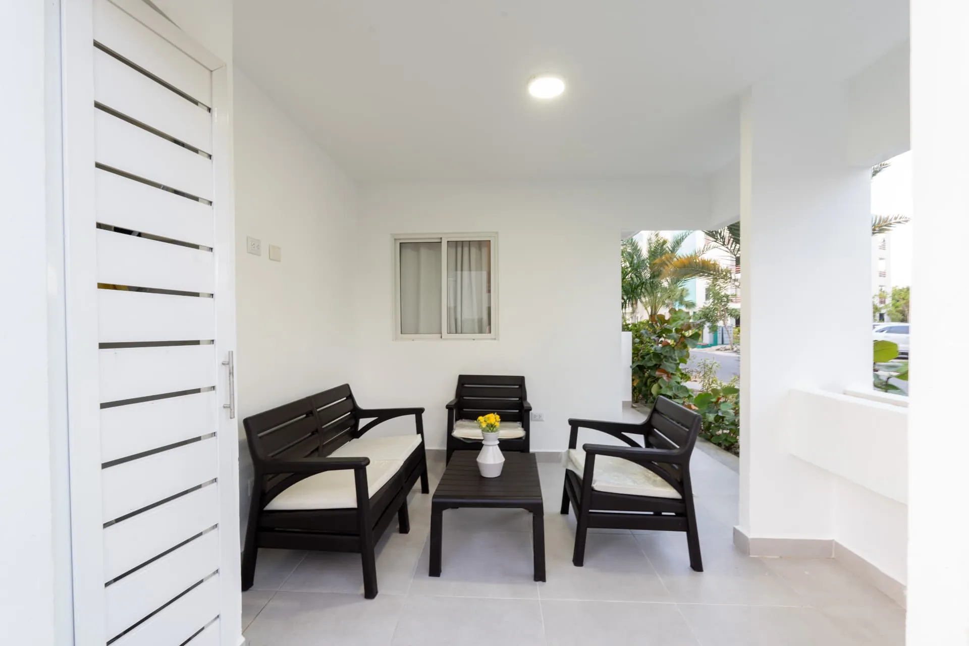 Private covered terrace with dark rattan lounge seating, coffee table and garden views