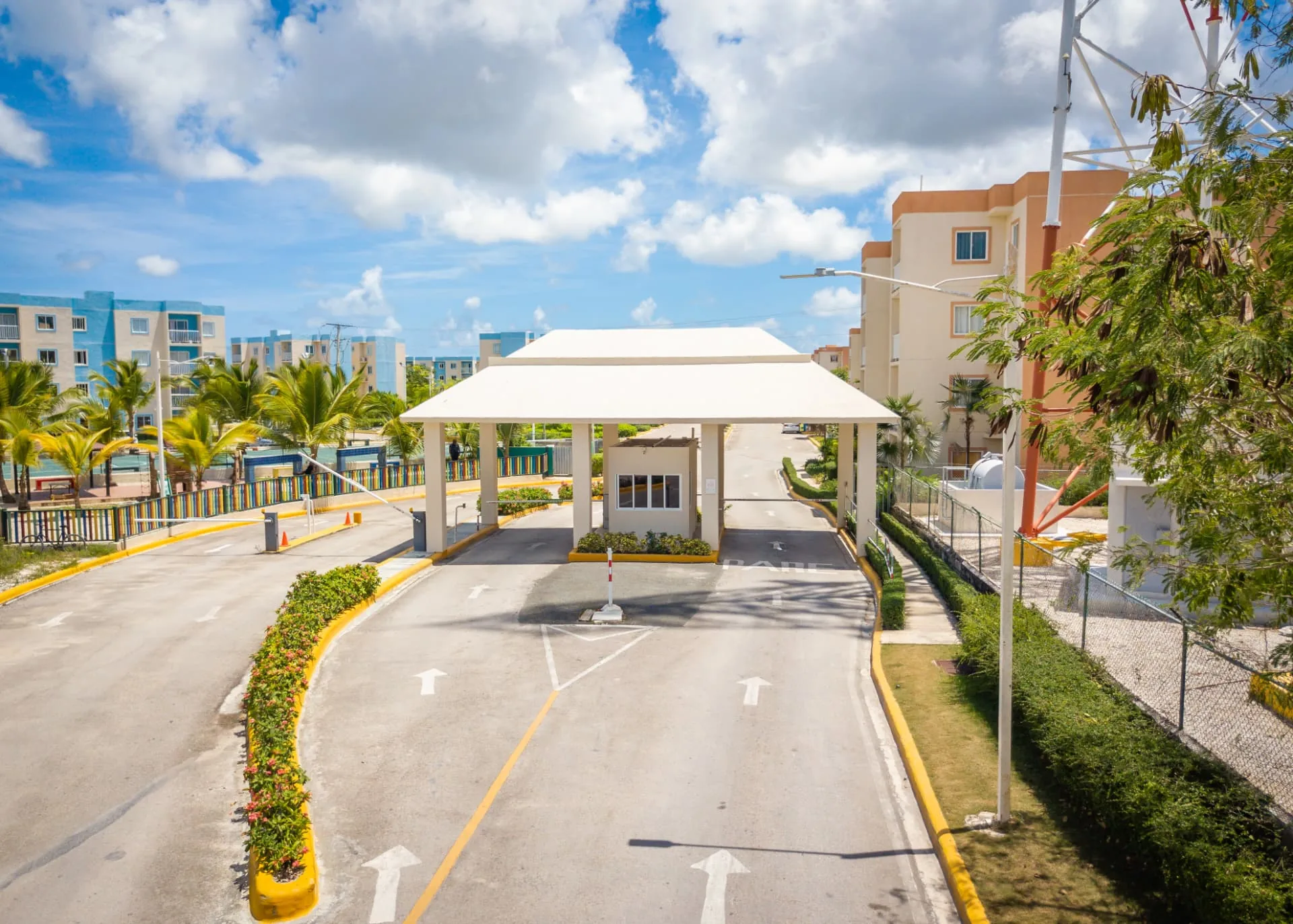 Gated community entrance with covered guard pavilion, palms and landscaped medians