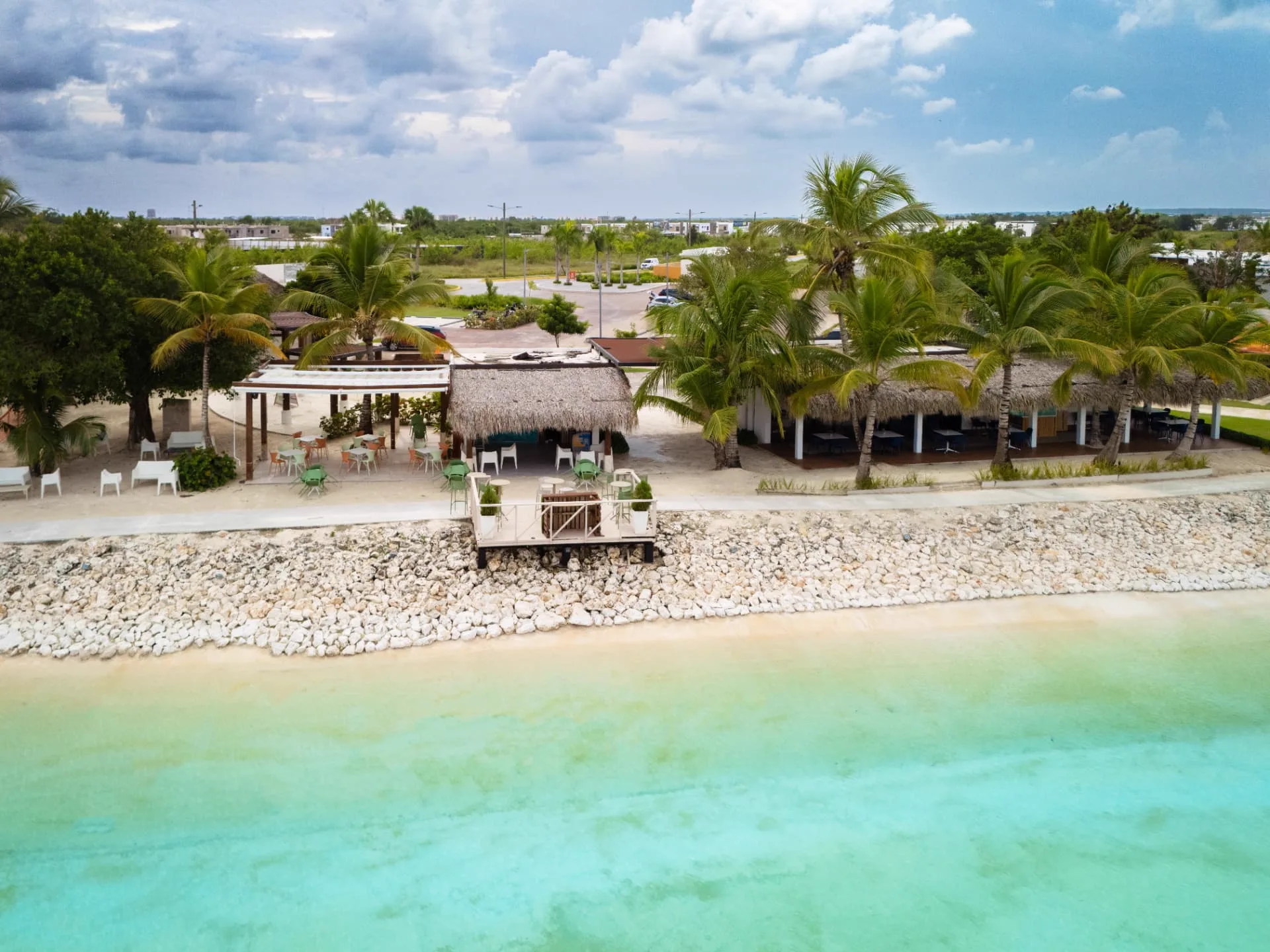 Aerial view of the lagoon beach club with thatched palapa bar, terraces and turquoise water