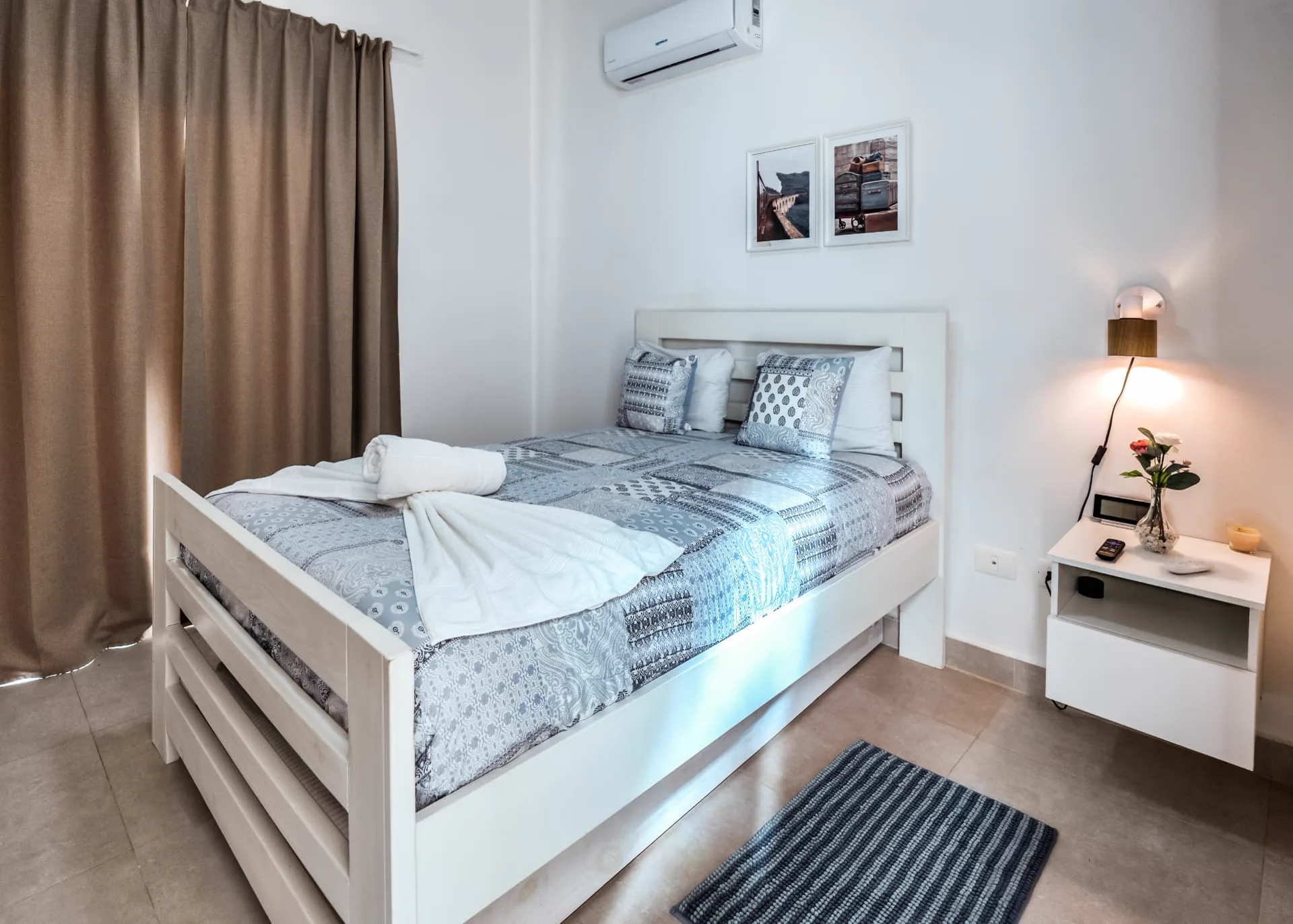 Guest bedroom with white timber bed, trundle base and bedside sconce lighting