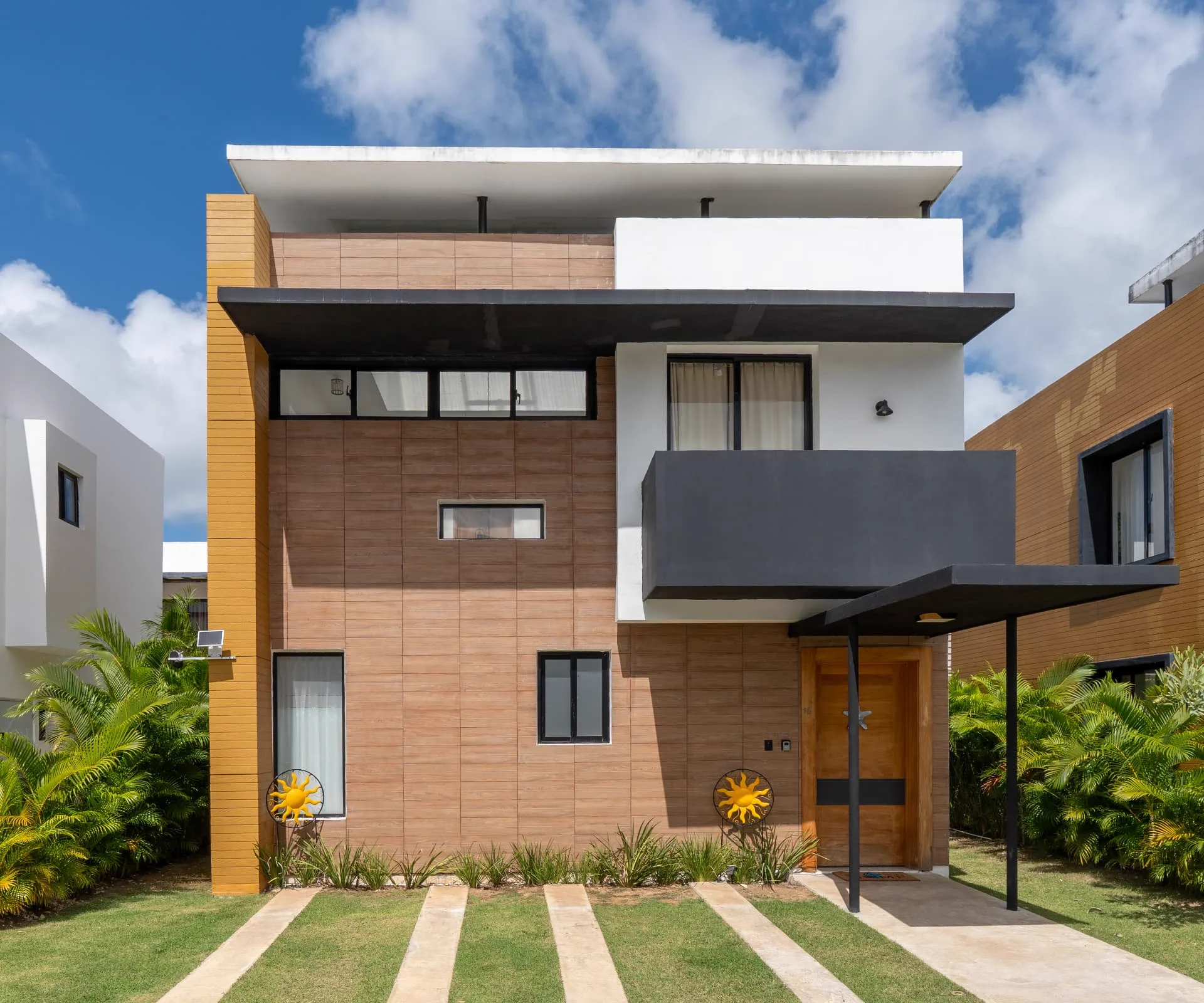 Two-level villa facade with timber-look cladding, ochre accent wall and covered entry canopy