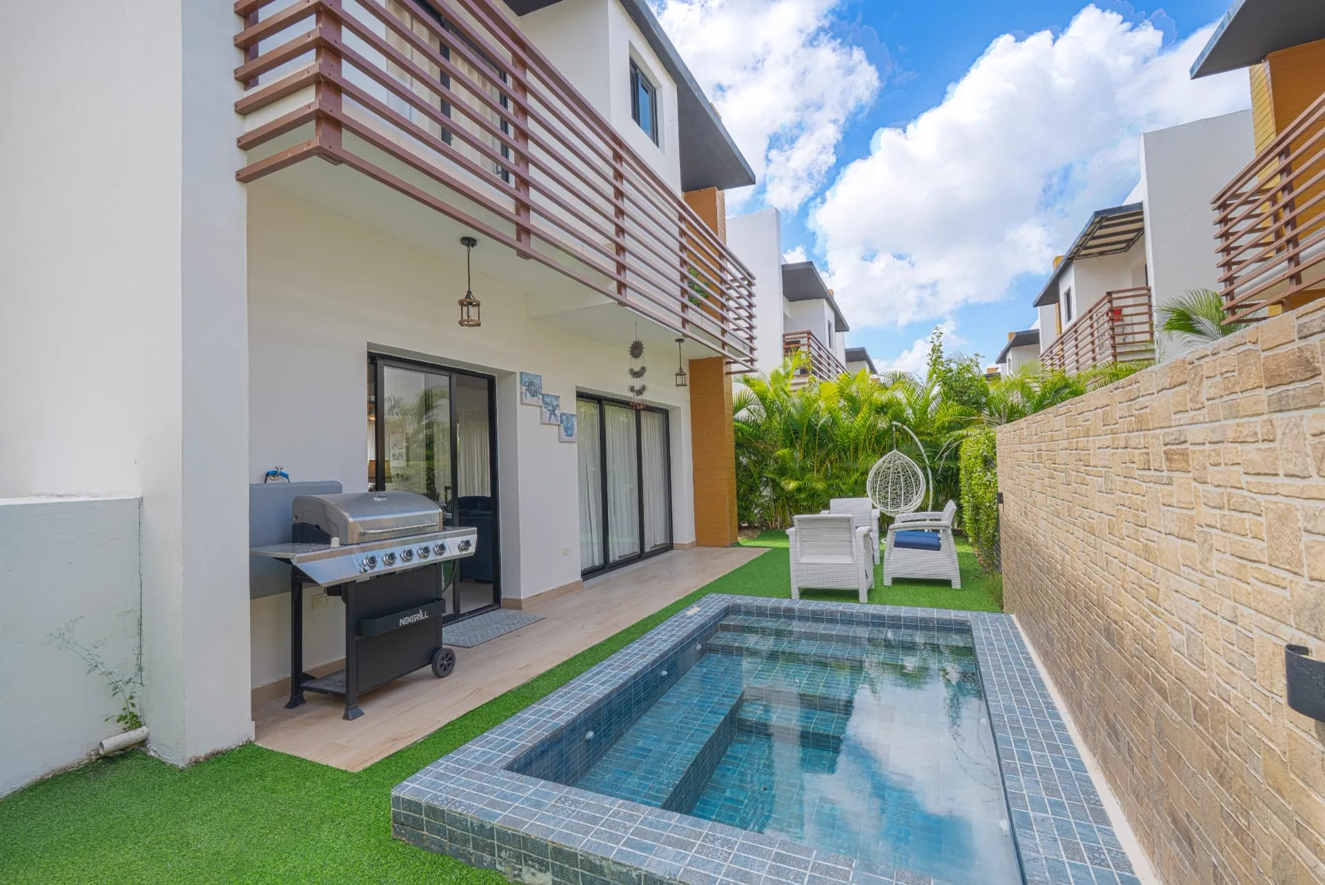 Private side terrace with mosaic plunge pool, gas grill, lounge seating and hanging egg chair