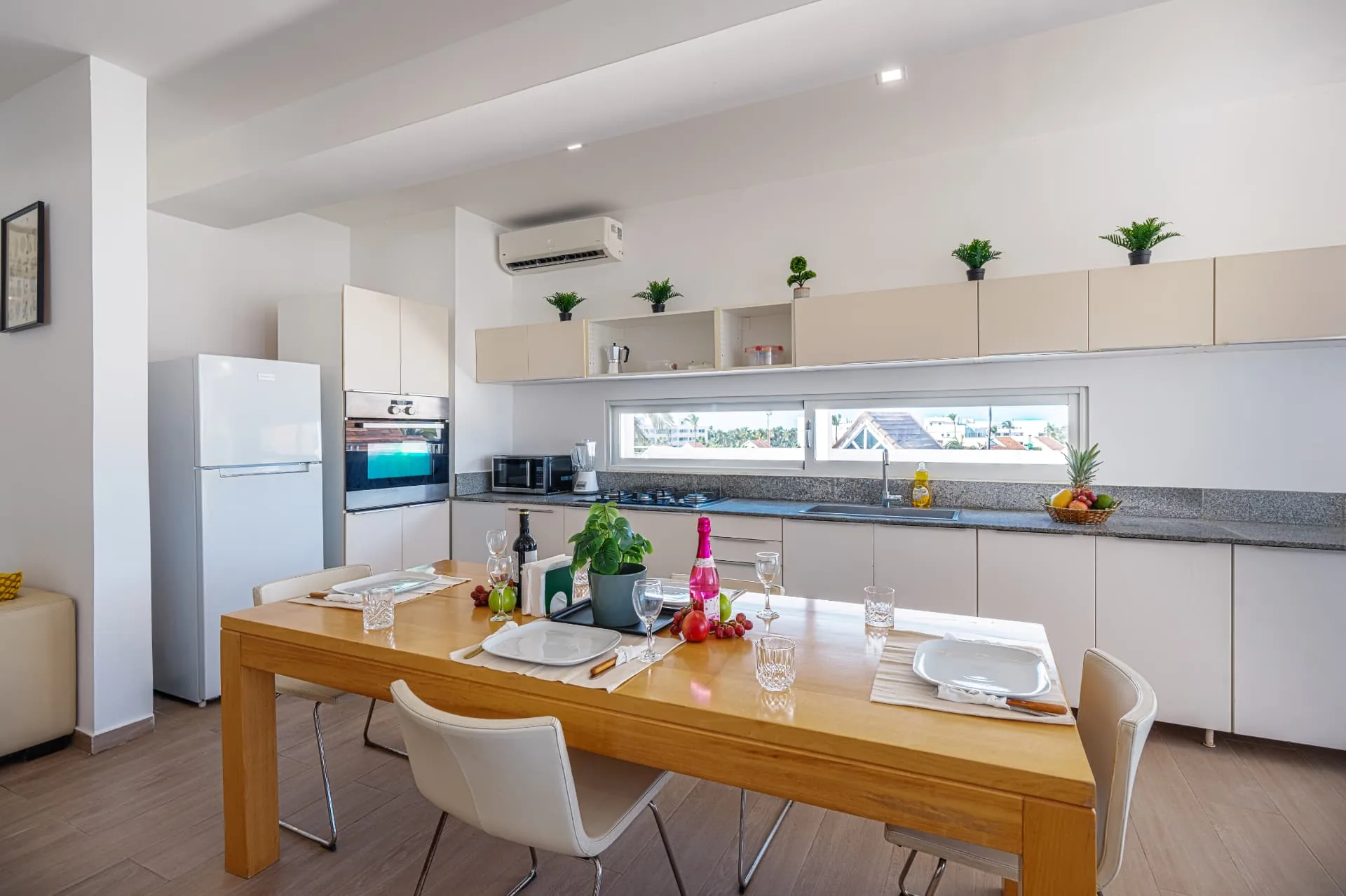 Open penthouse kitchen with pale cabinetry, granite counters and a timber dining table set for four