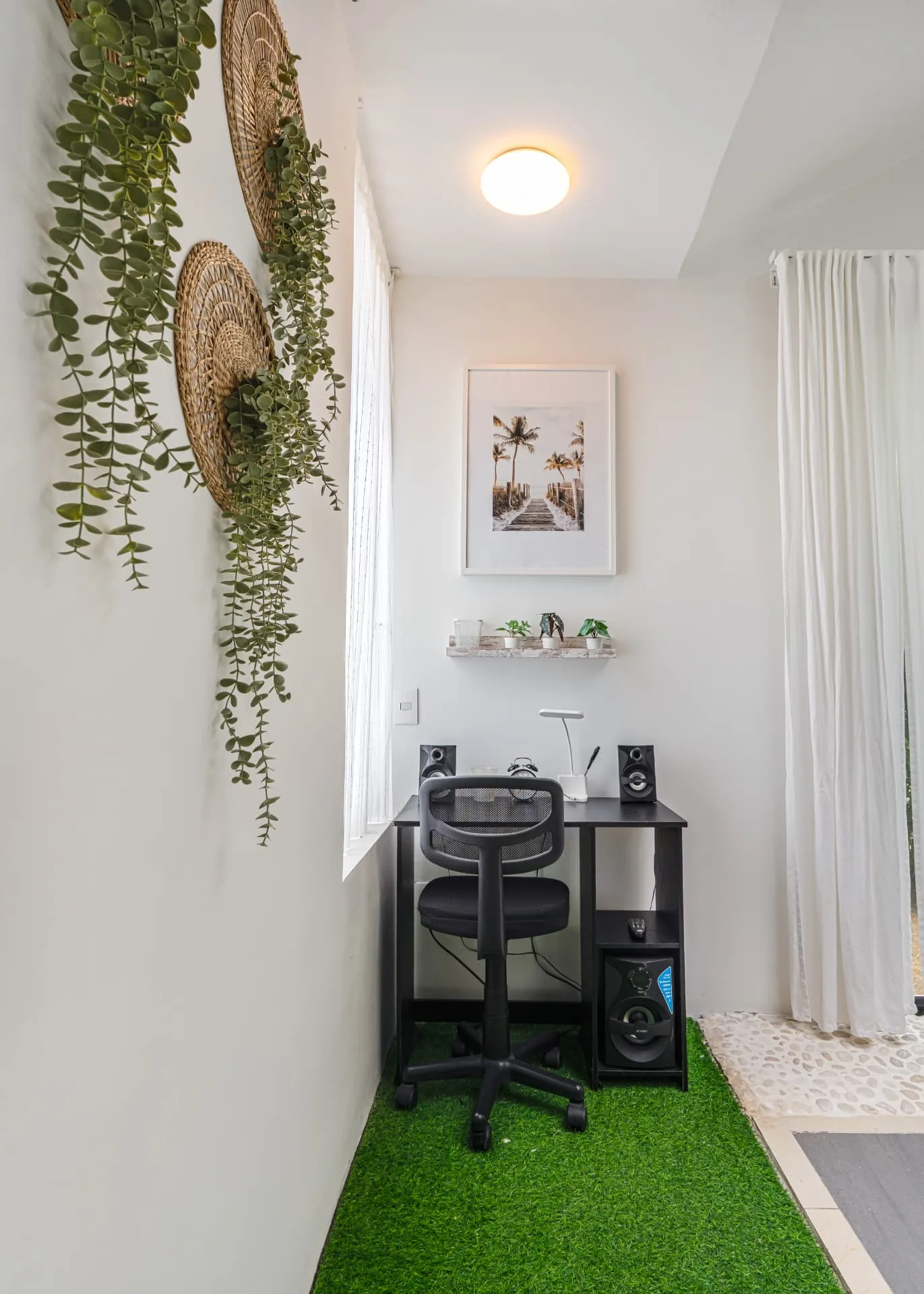 Compact home office nook with black desk, framed palm print and woven wall decor