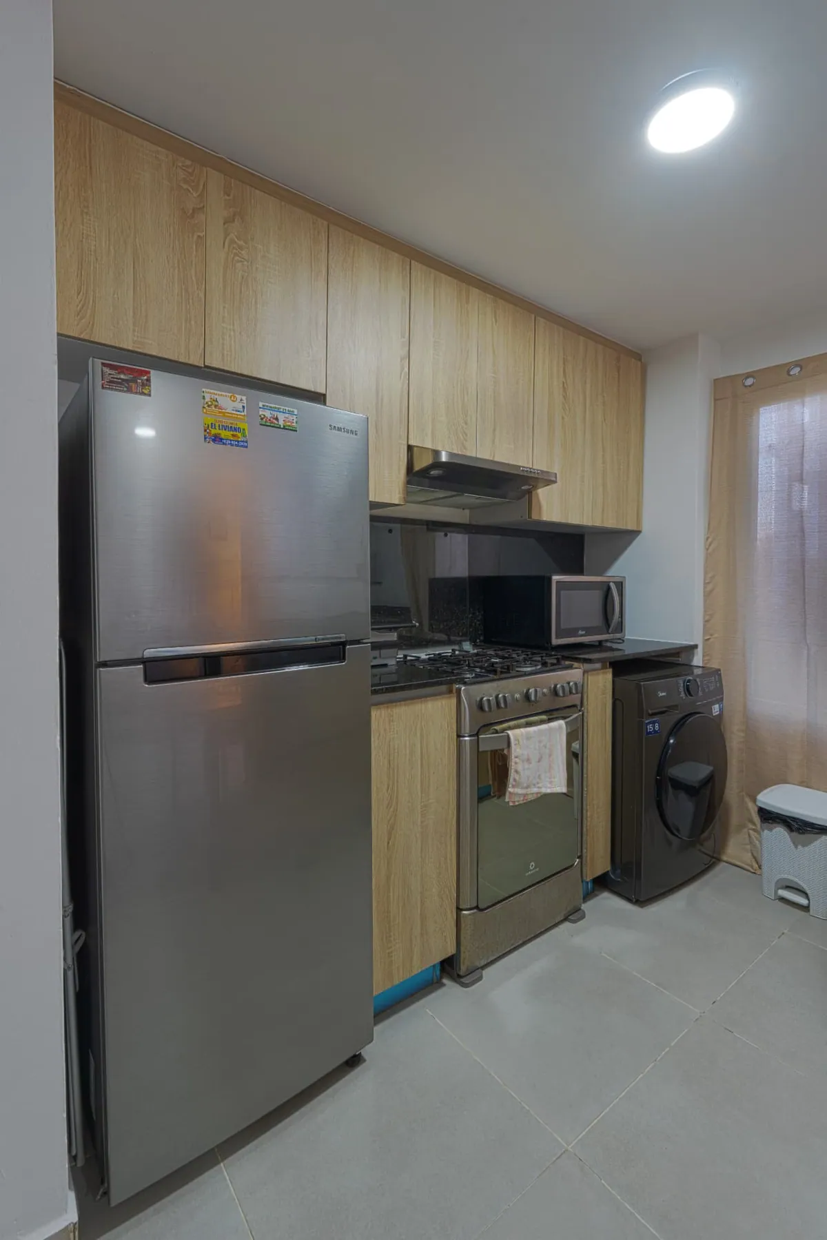 Timber-front kitchen with stainless refrigerator, gas range, microwave and washing machine