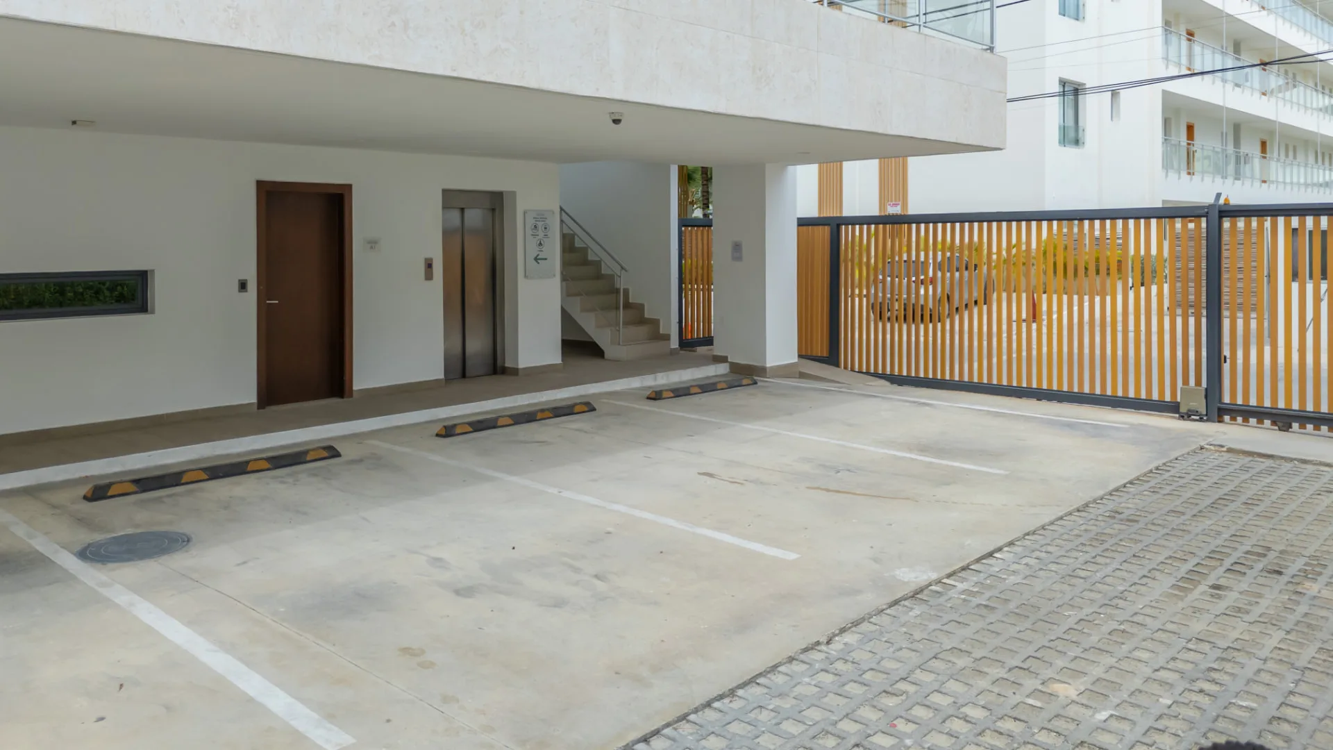 Ground-floor covered parking with elevator access and slatted timber security gate