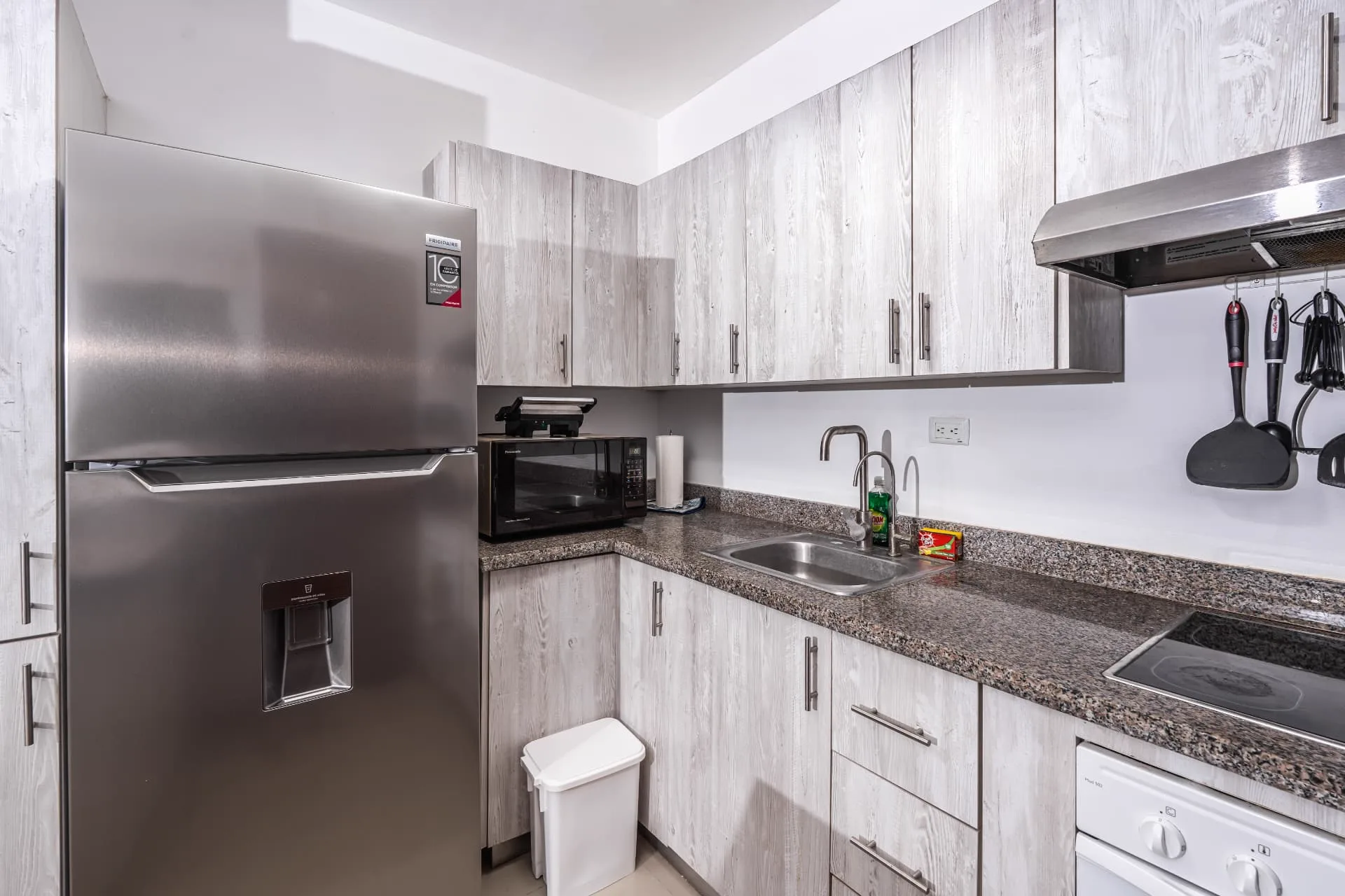 Kitchen corner with stainless steel refrigerator, granite counters, microwave and induction cooktop