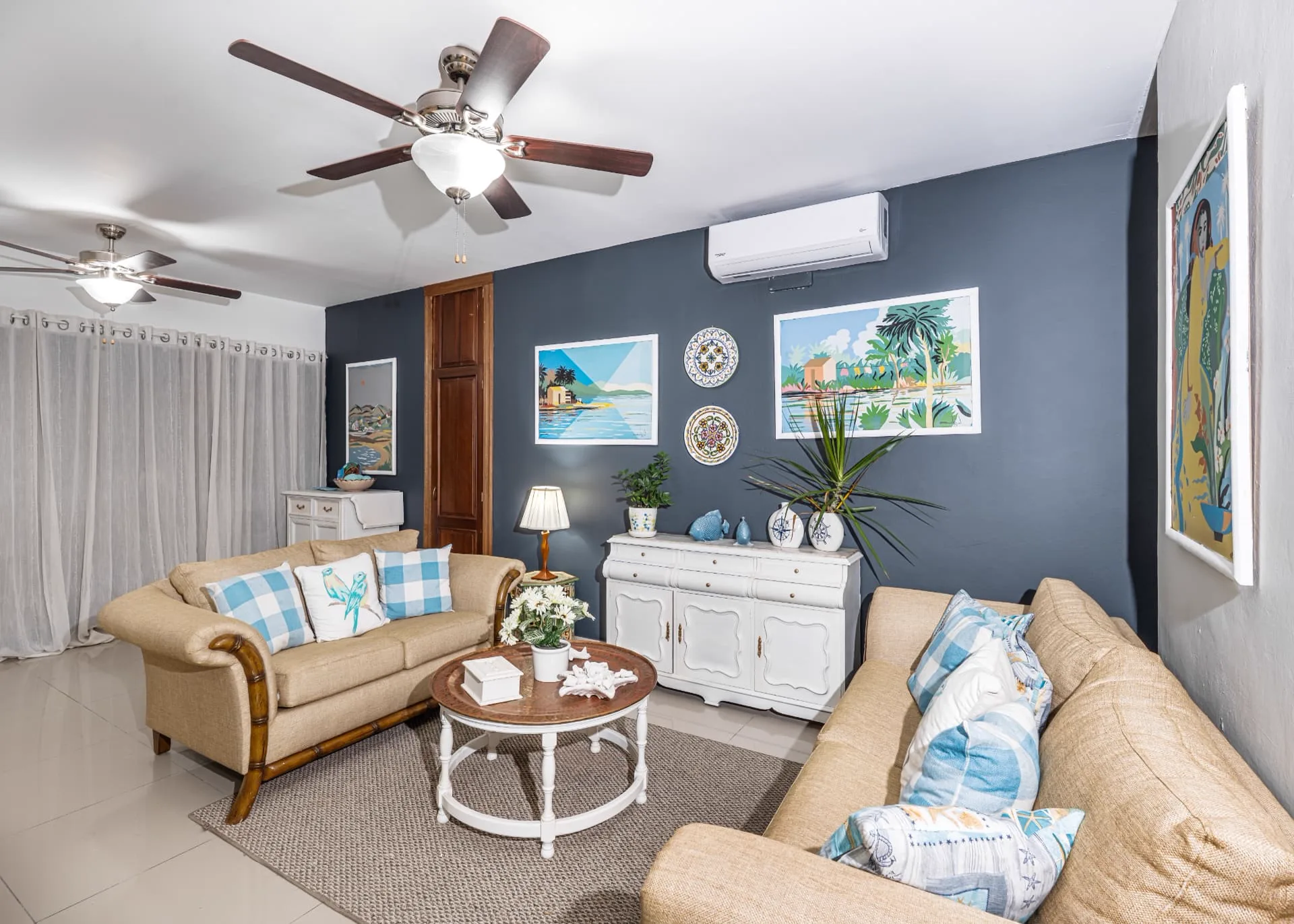 Second view of the living room showing both ceiling fans, sheer curtains, white sideboard and the sisal rug