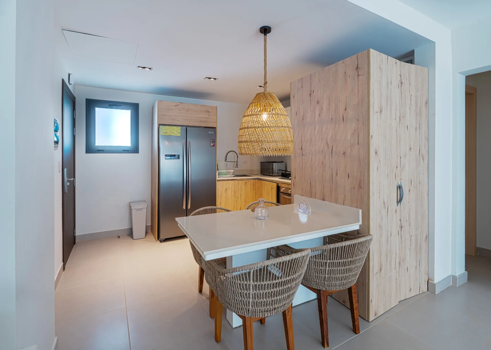 Dining bar with rattan chairs and rope pendant light beside the entry hall and kitchen