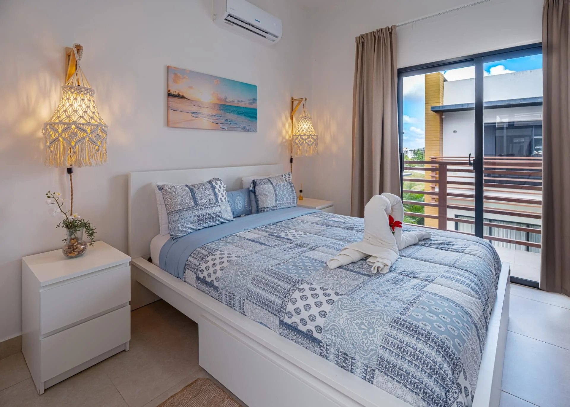Rental bedroom with macramé pendant lights, blue patterned bedding and balcony doors