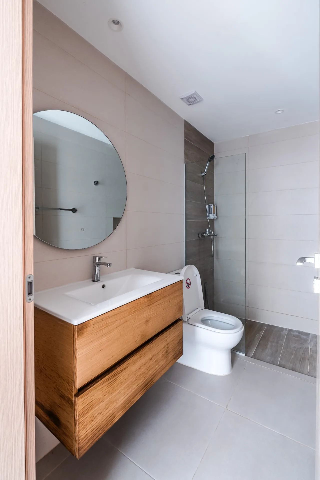 Bathroom with round mirror, timber floating vanity and a walk-in glass shower