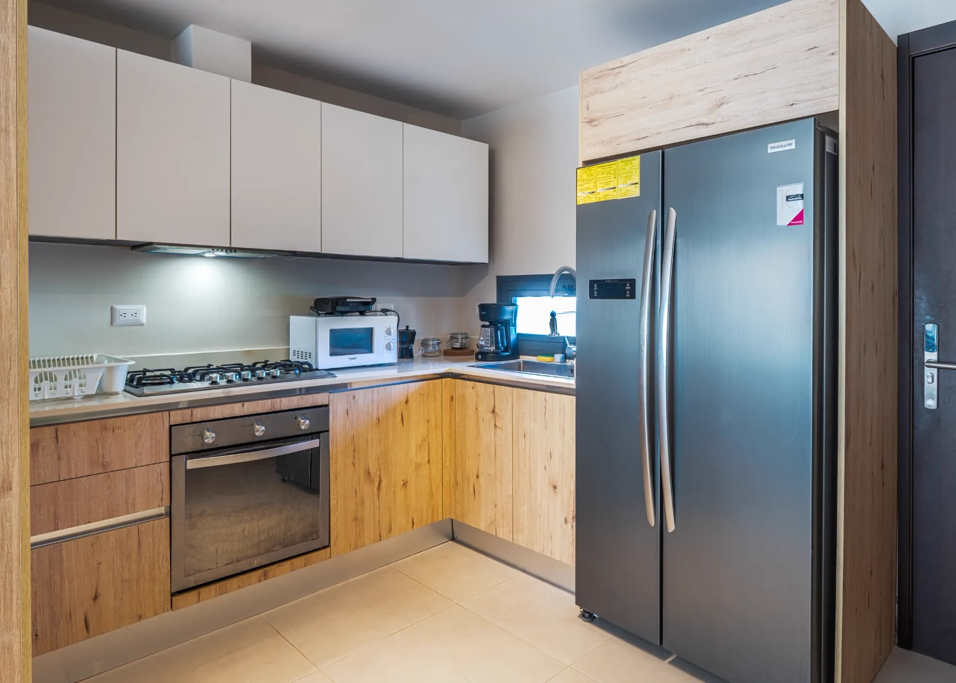 L-shaped kitchen with oak cabinetry, gas cooktop, built-in oven and stainless steel refrigerator