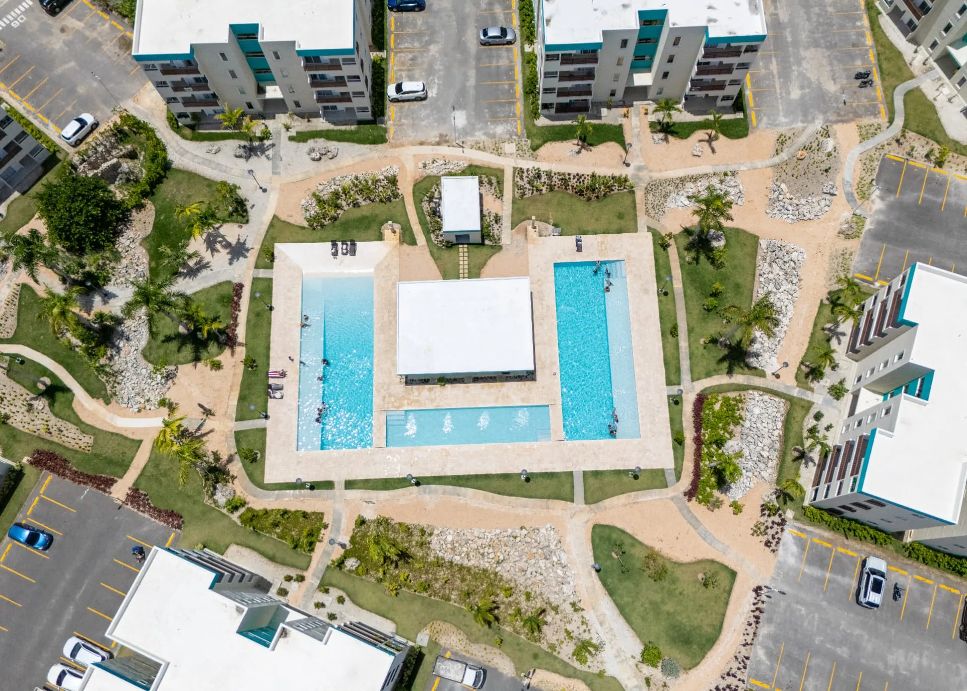Direct overhead drone view of the twin pools, pavilion and stone deck framed by palms