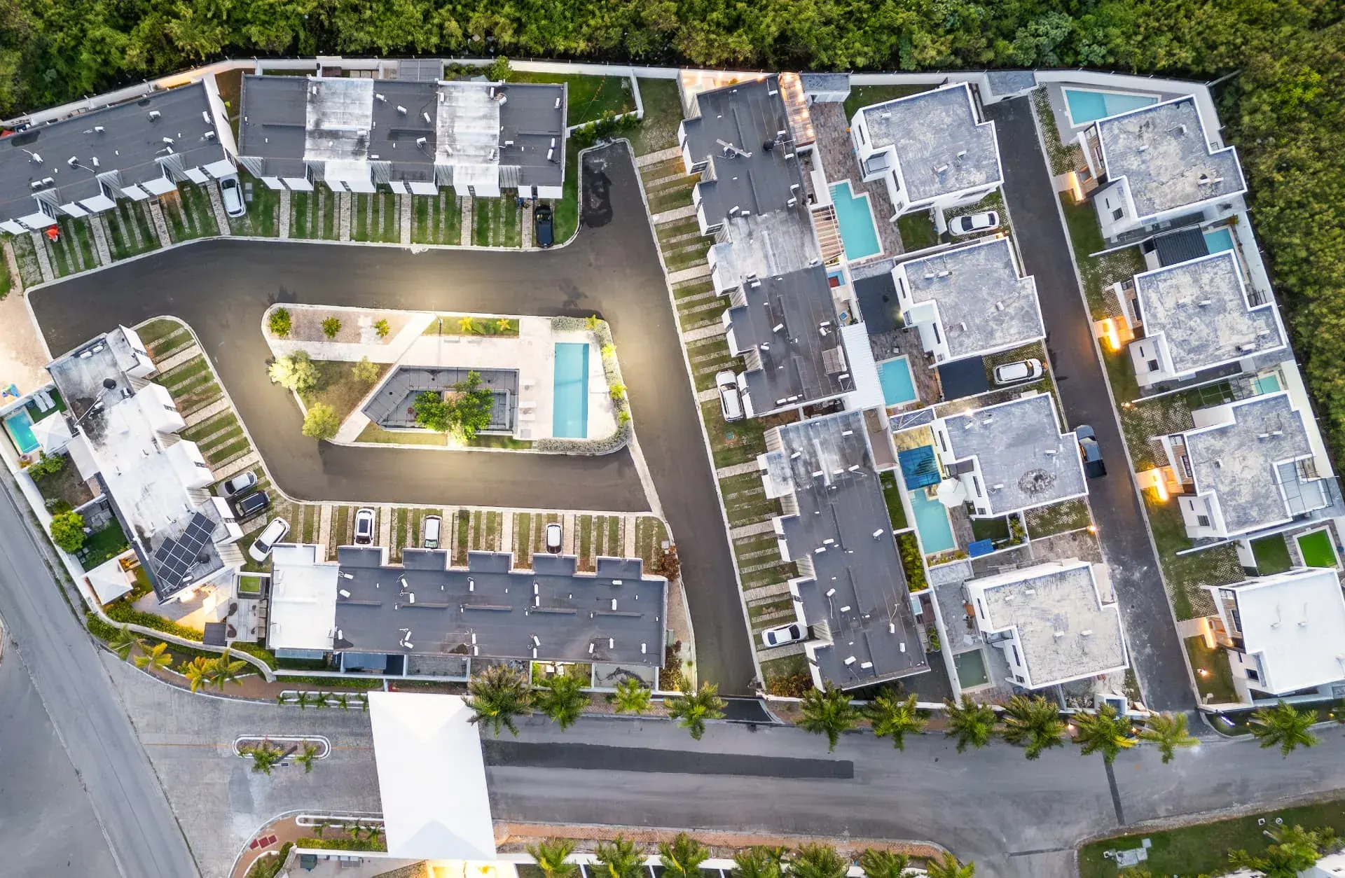 Top-down aerial of a gated villa community at dusk showing private plunge pools and driveways