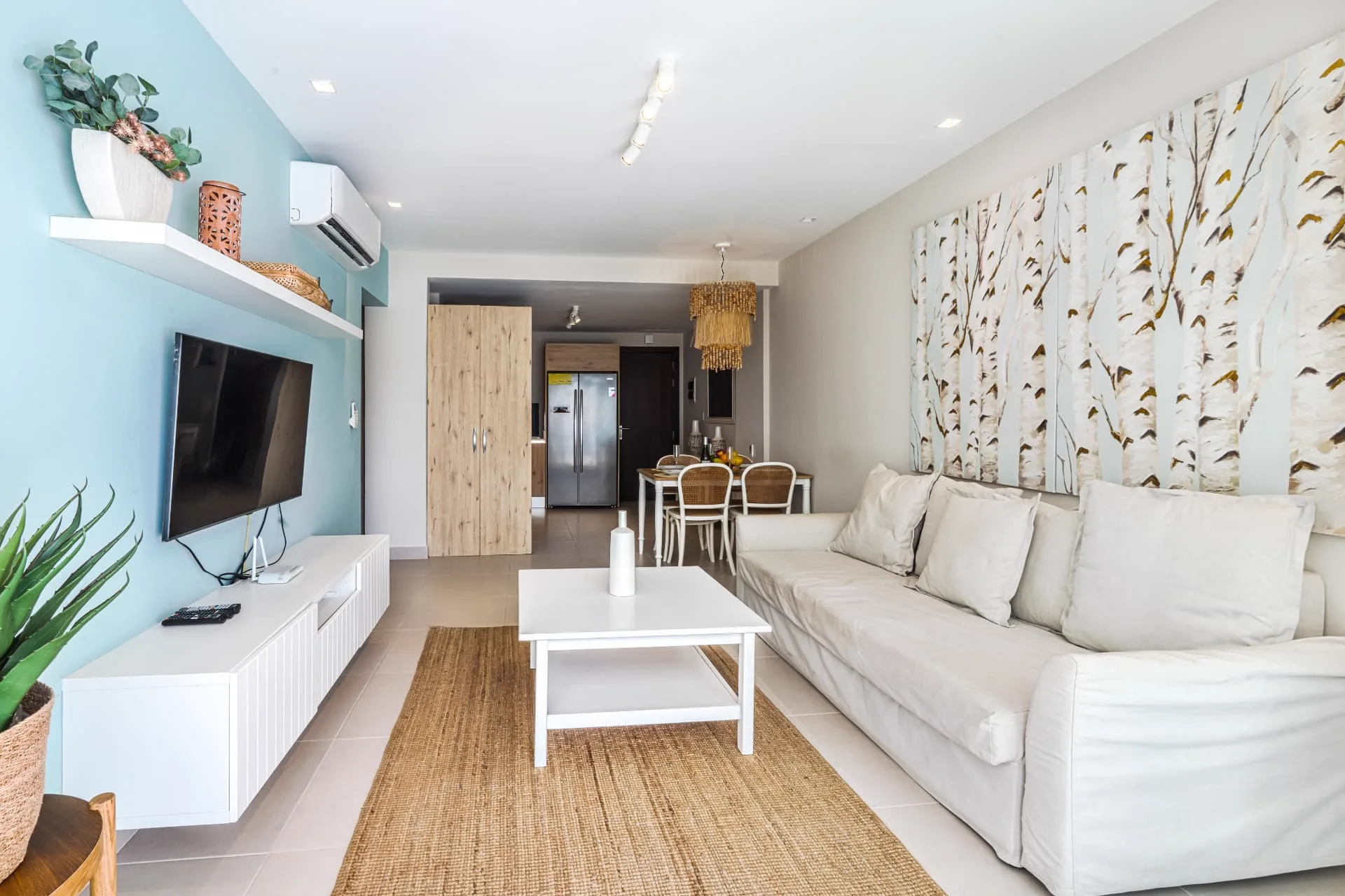 Living room looking through to the rattan dining set and kitchen, with turquoise media wall and jute rug