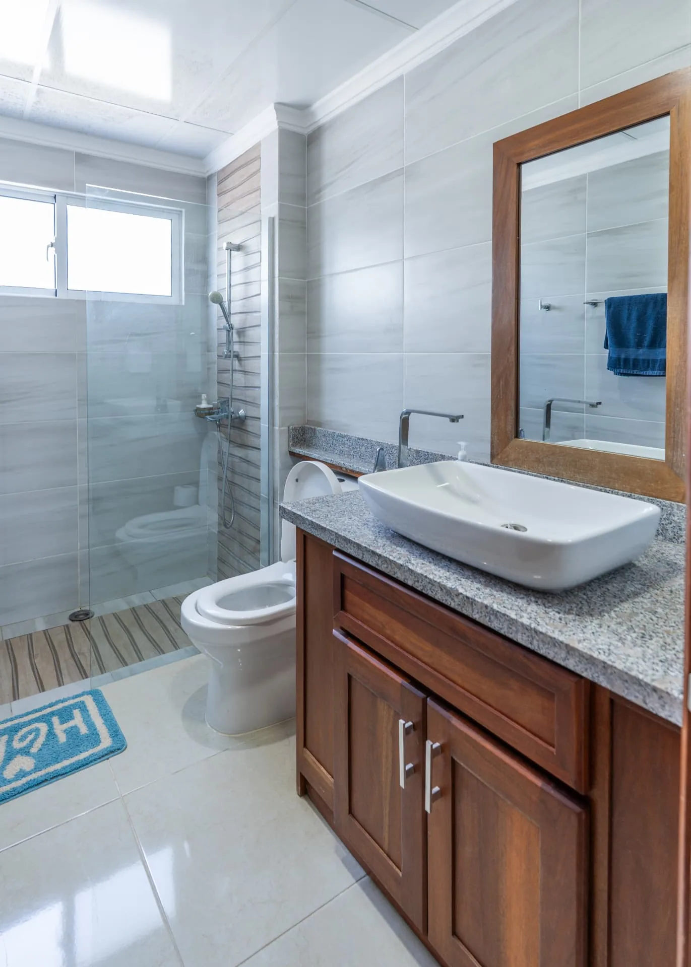 Second bathroom with walk-in glass shower, mahogany vanity, vessel basin and marbled porcelain walls