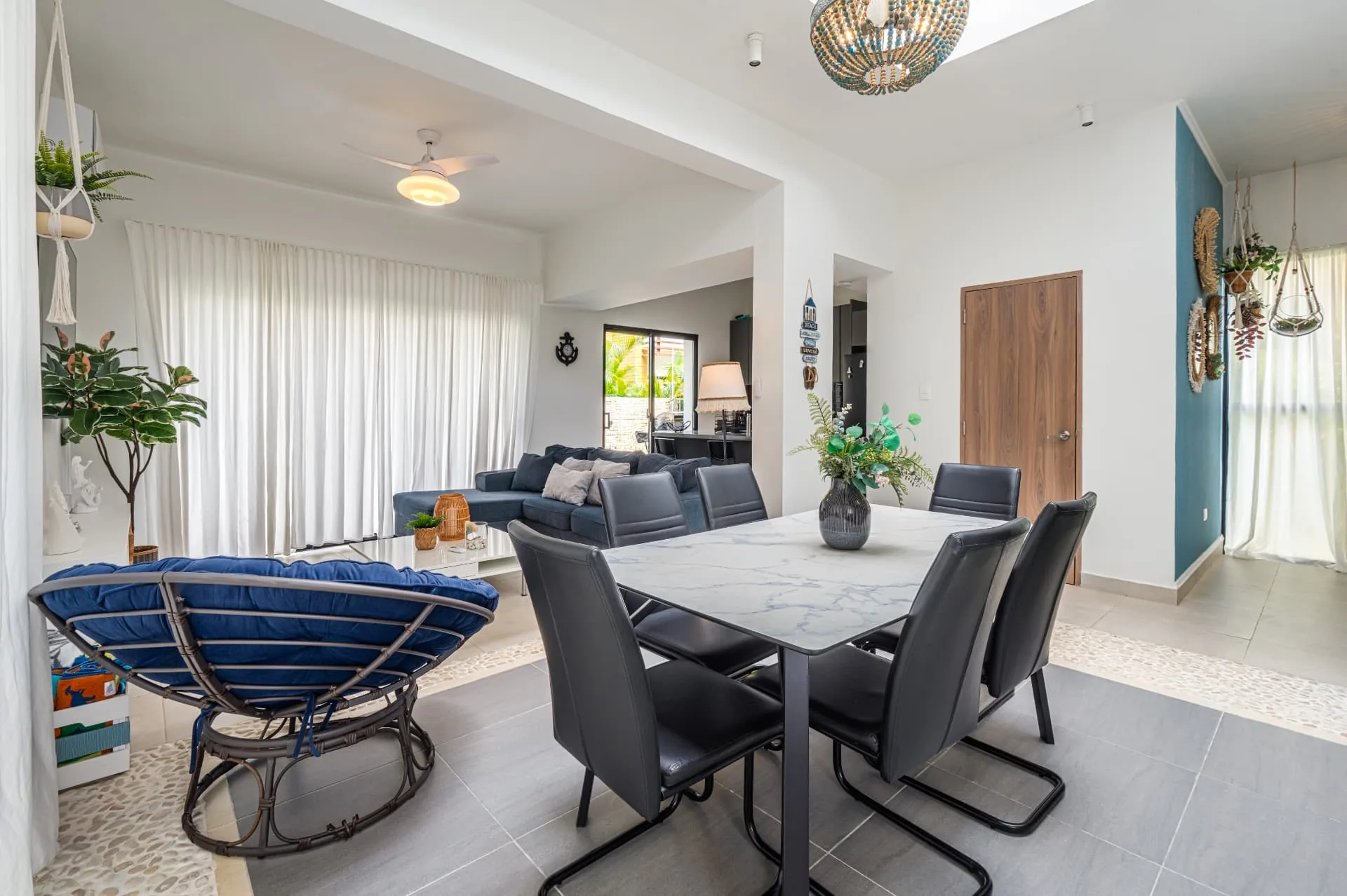Marble dining table beside the living room with teal feature wall and open kitchen beyond