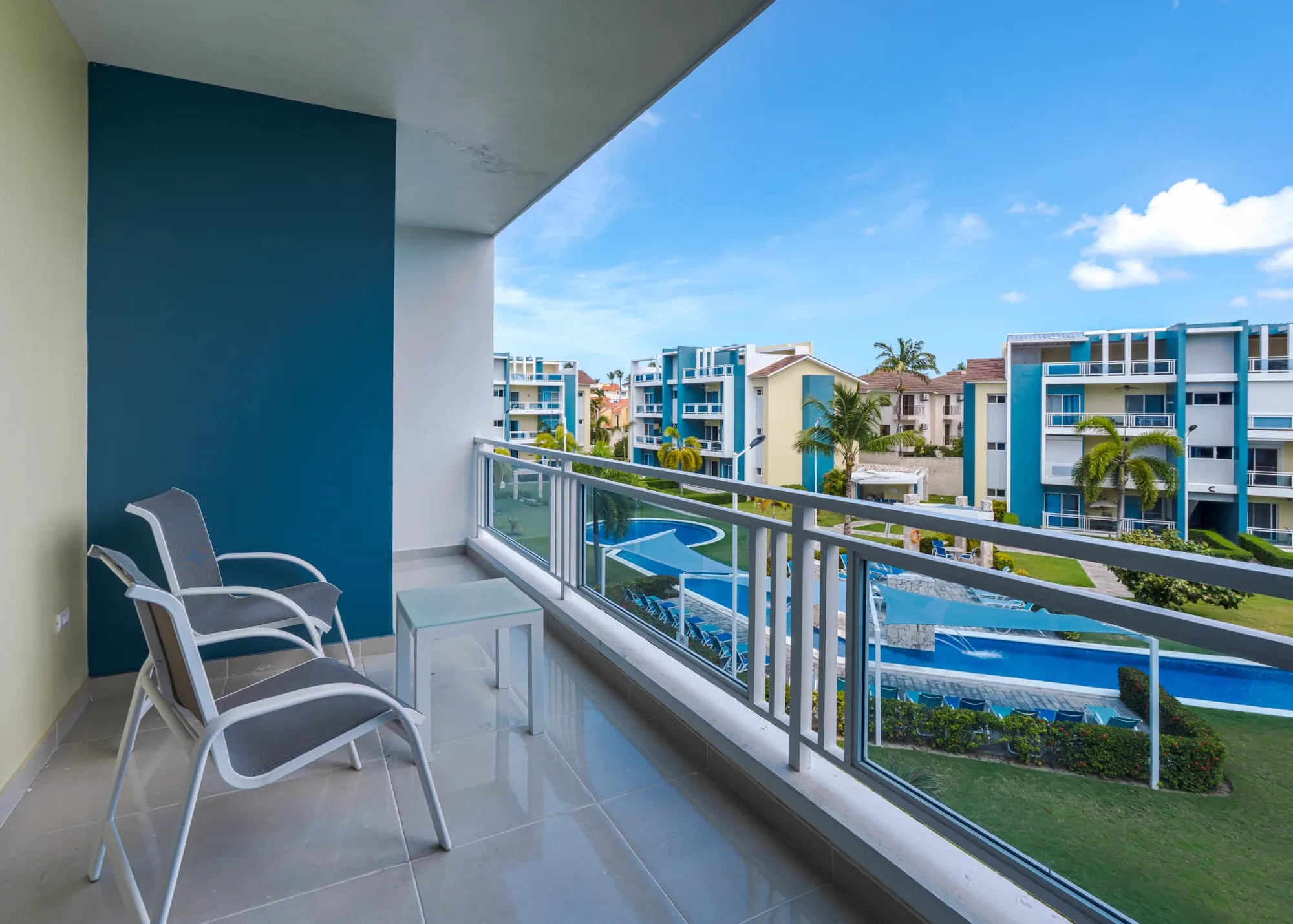 Covered balcony at Eden with two loungers looking over the resort pool deck, sun loungers and palm gardens