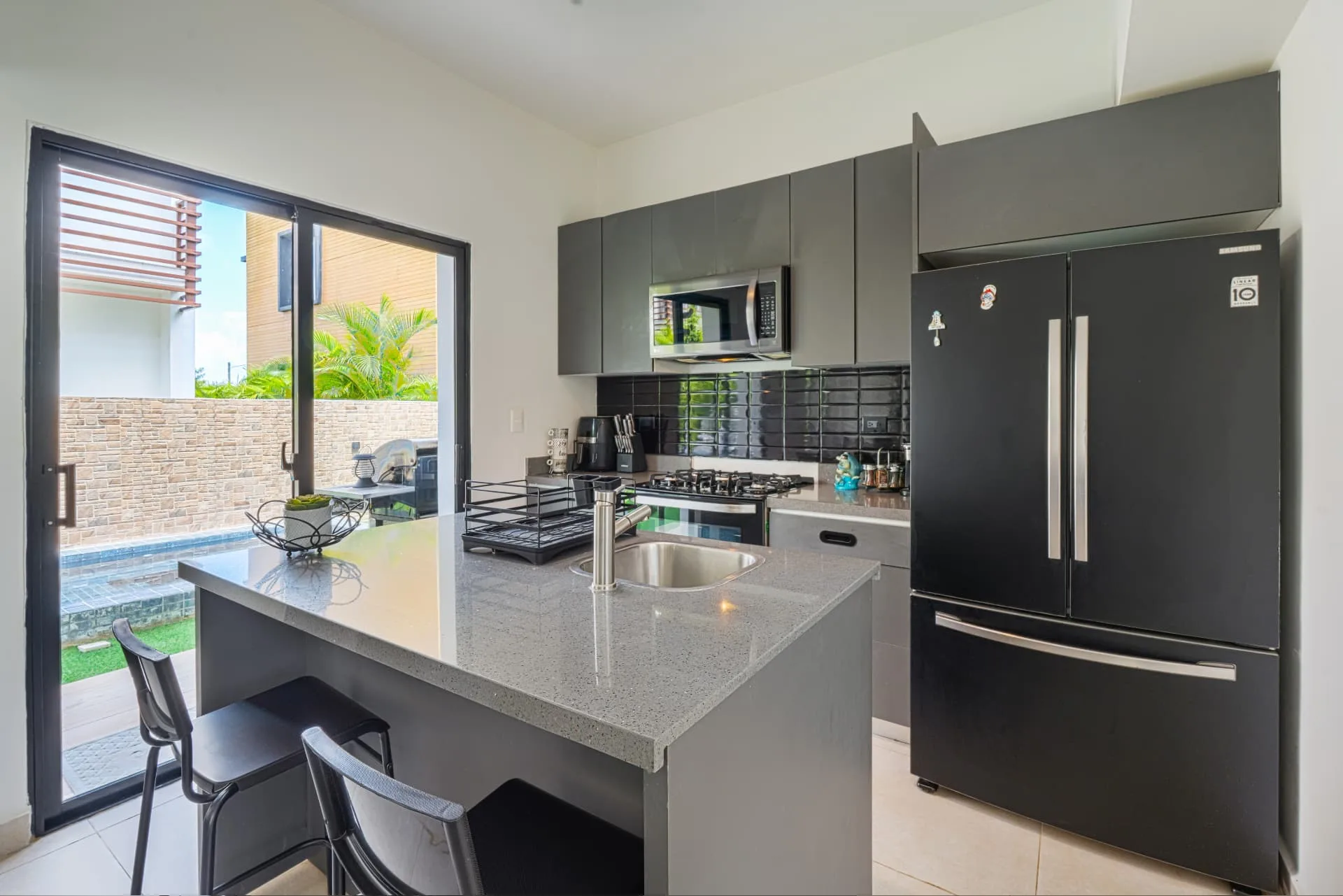 Modern kitchen with graphite cabinets, quartz island breakfast bar and terrace access