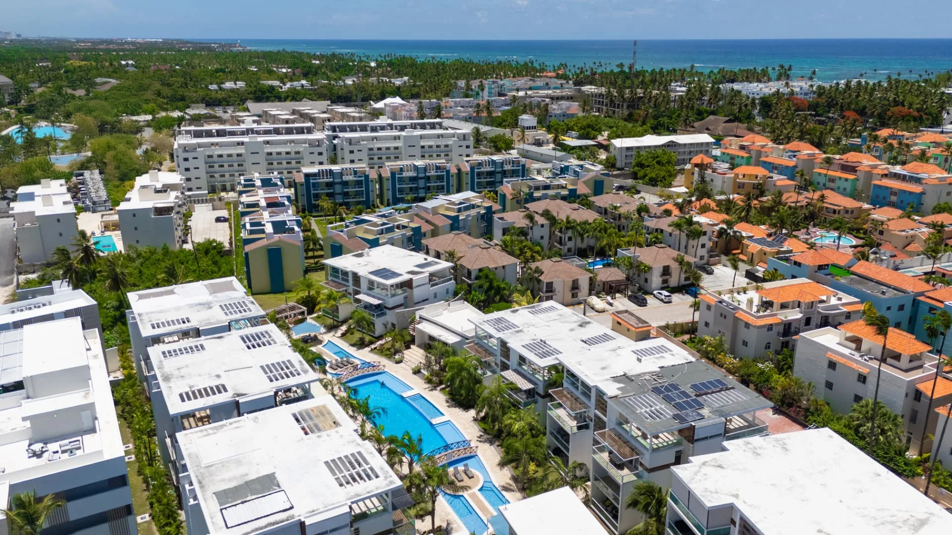 Aerial view of a Punta Cana Village condominium community with pools, palms and the Caribbean coastline beyond