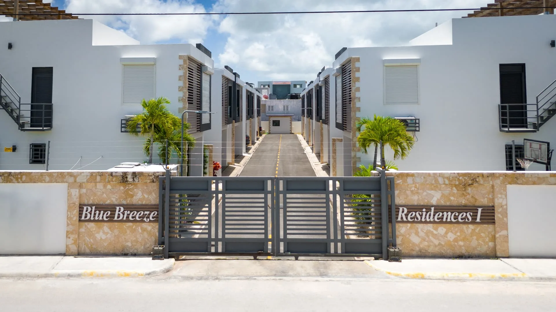 Gated entrance to Vista Cana Residence with stone-clad walls and palm-lined driveway