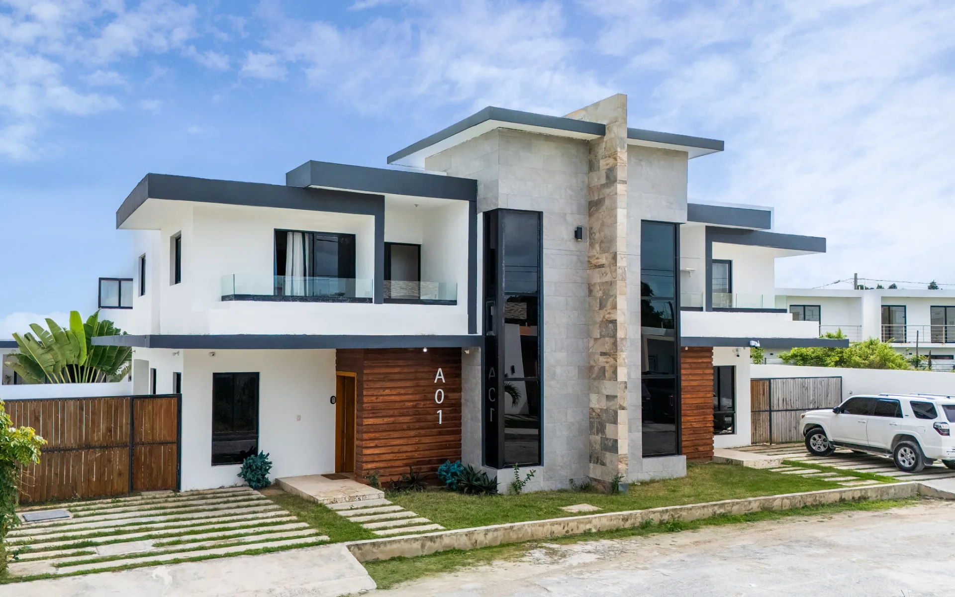 Modern two-storey villa with stone-clad stair tower, timber cladding and glass balcony railings
